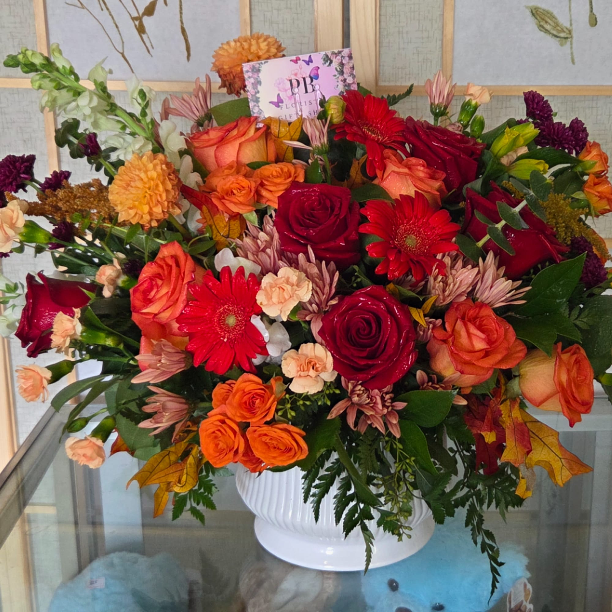 Mixed bouquet of roses, gerbera daisies, and mums in a white vase