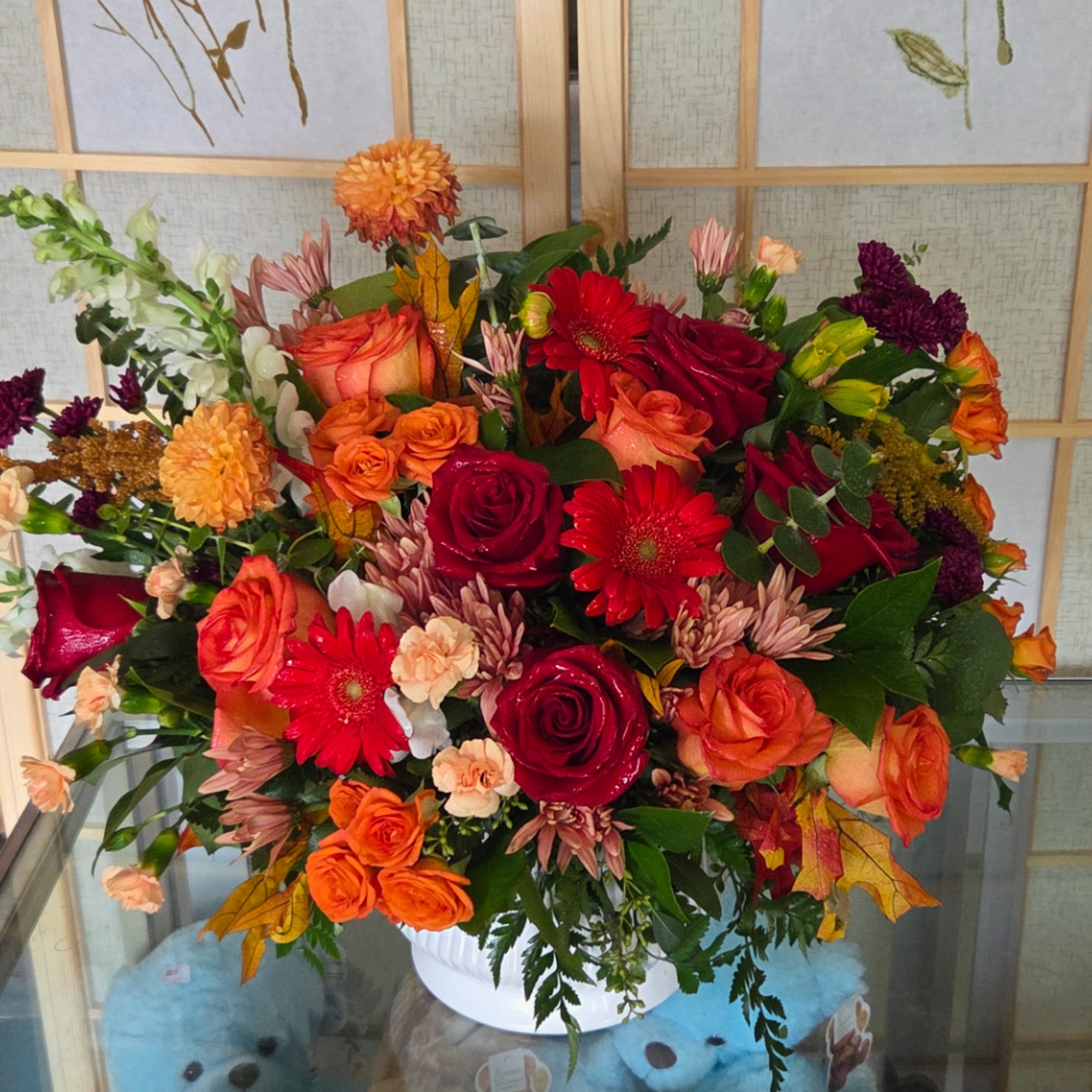Mixed bouquet of red, orange, and peach flowers in a white vase, photo 4 of 4