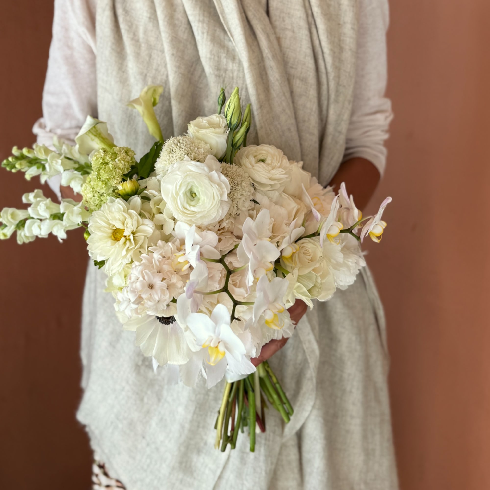 White bridal bouquet with orchids, ranunculus, and calla lilies