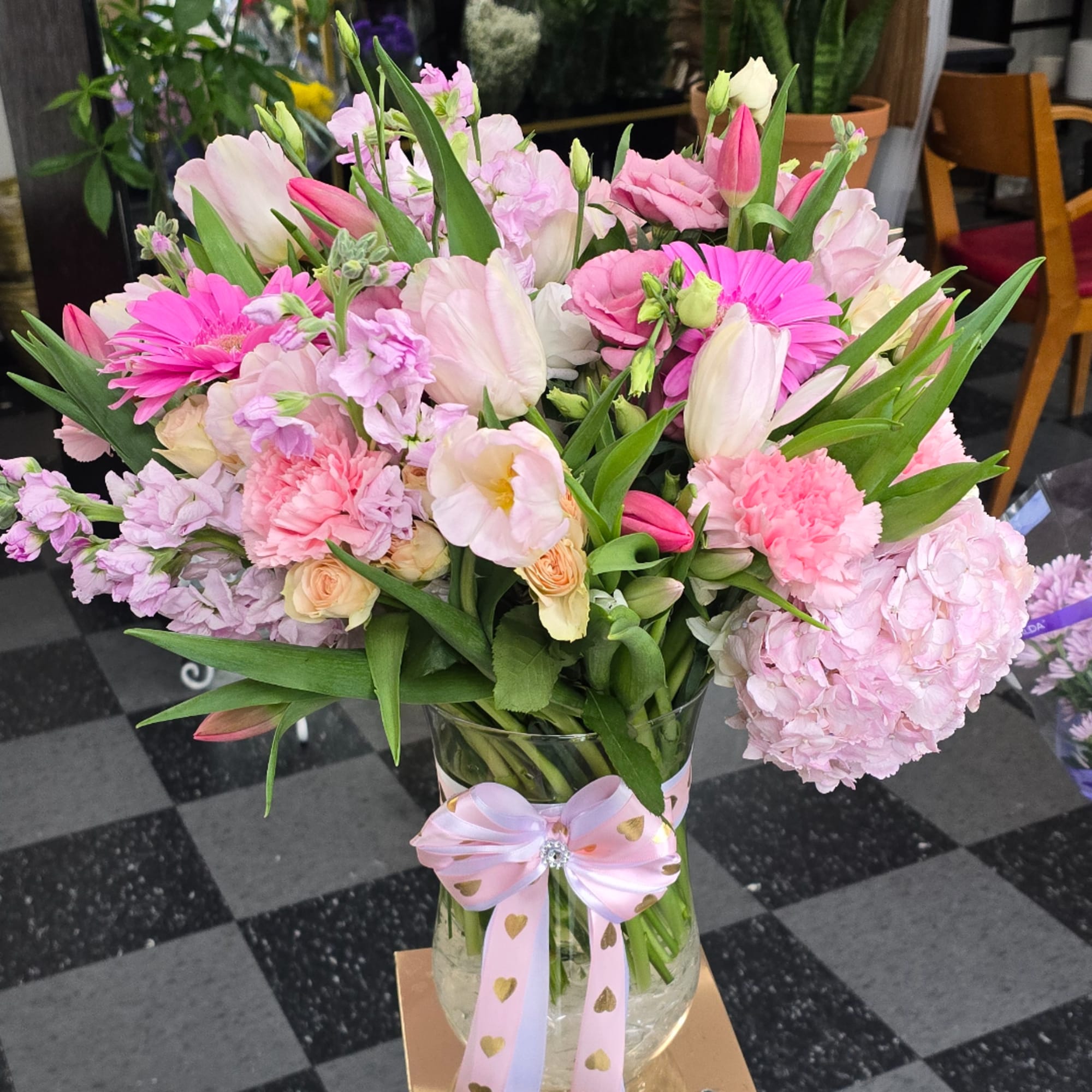 Pink and white mixed bouquet in a glass vase with a ribbon bow