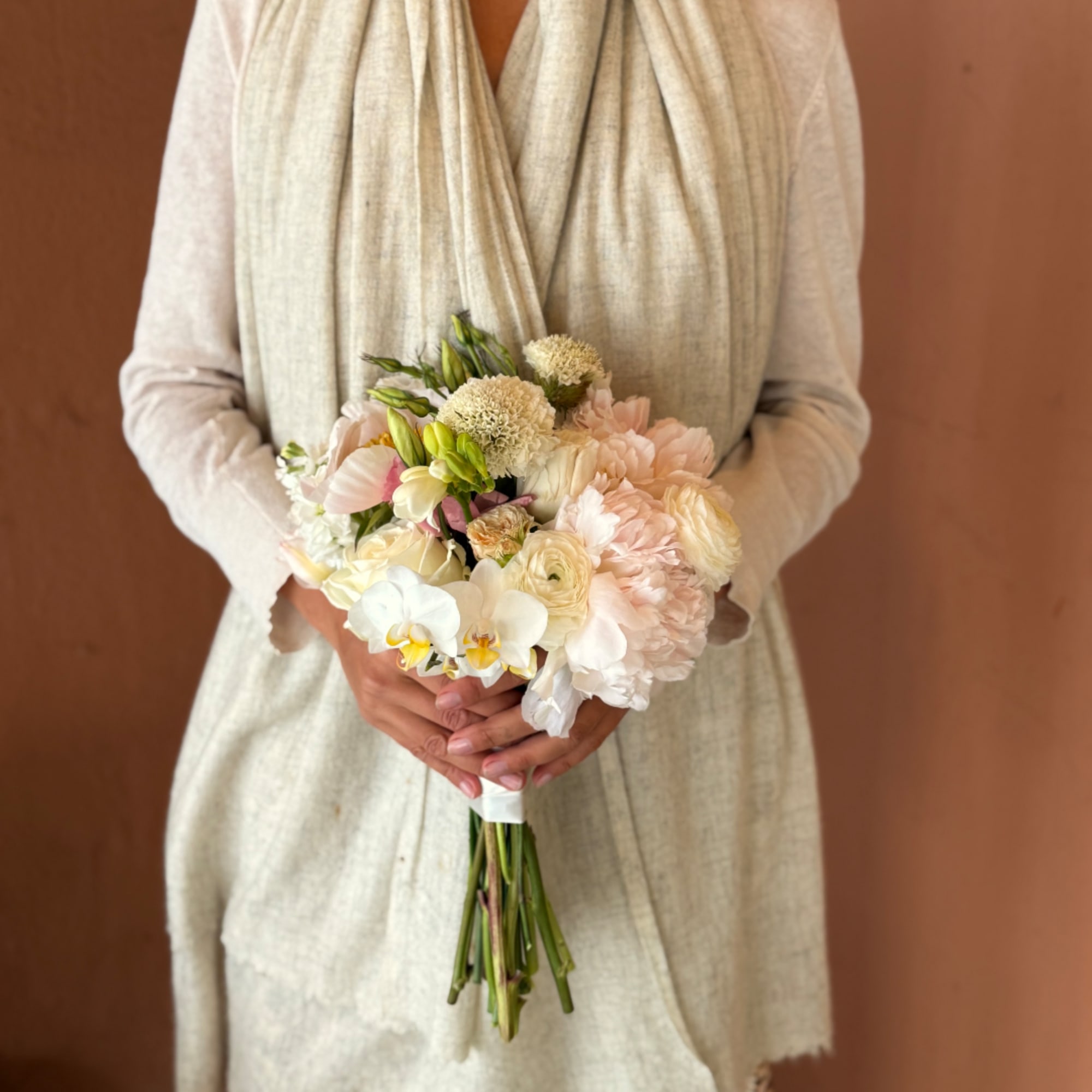 Person holding a pale blush and white bridal bouquet