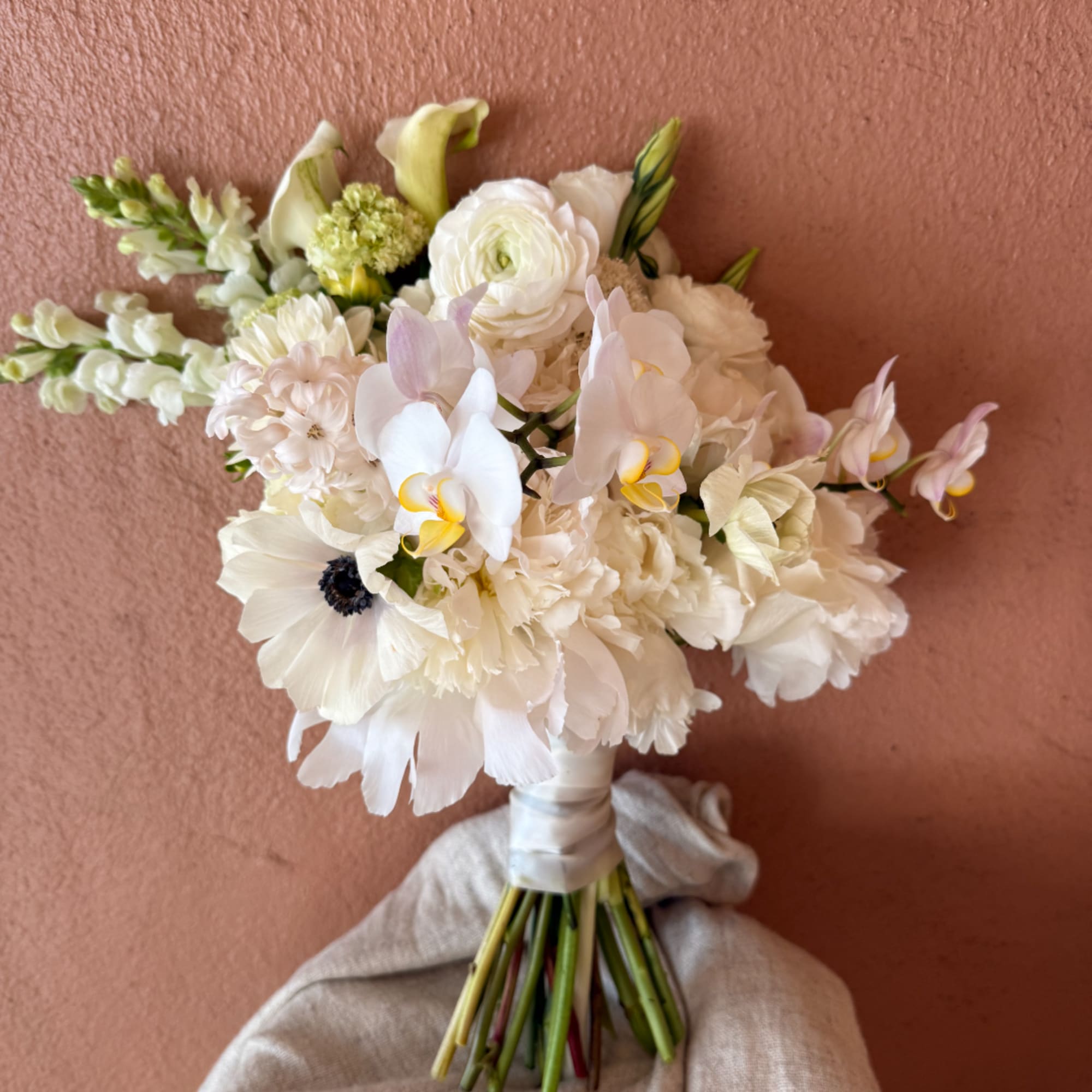 White bridal bouquet with orchids, ranunculus, and calla lilies