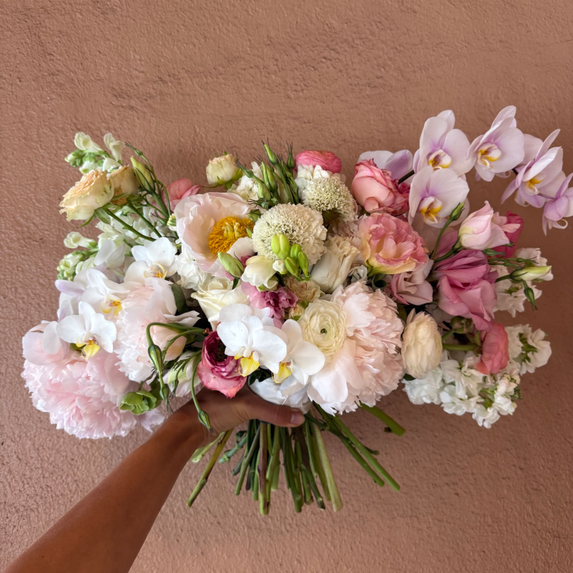 Handheld bouquet of pale pink, white, and lavender flowers
