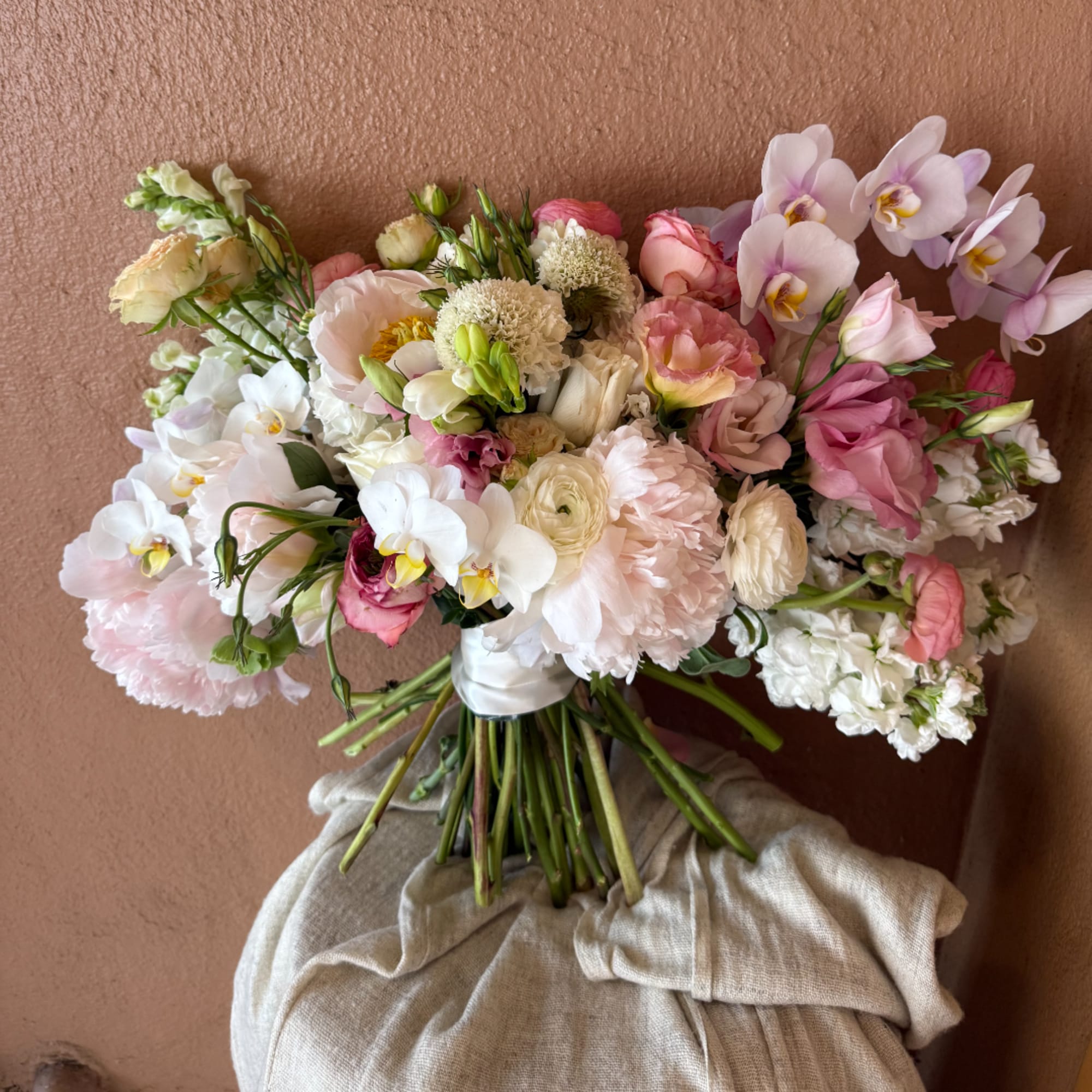 Pink and white wedding bouquet with orchids, roses, and ranunculus