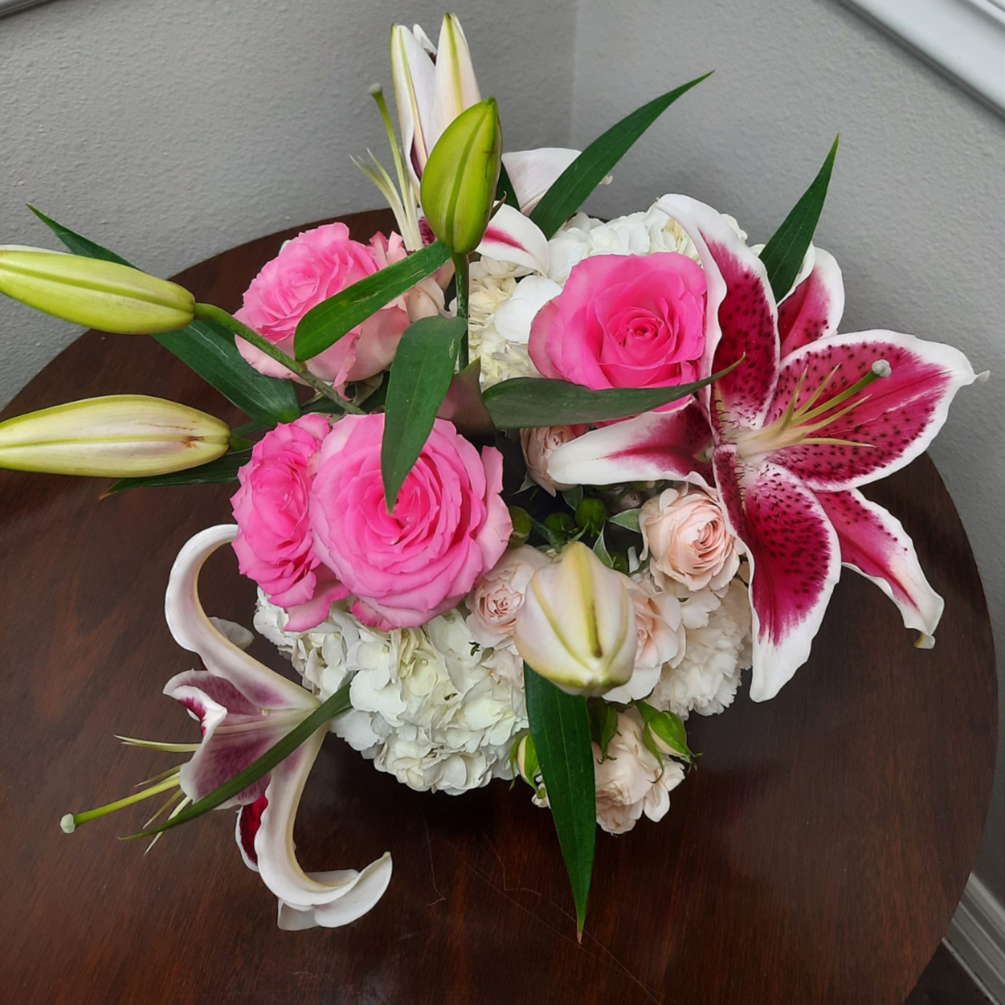 Pink roses and white lilies arranged in a low bouquet