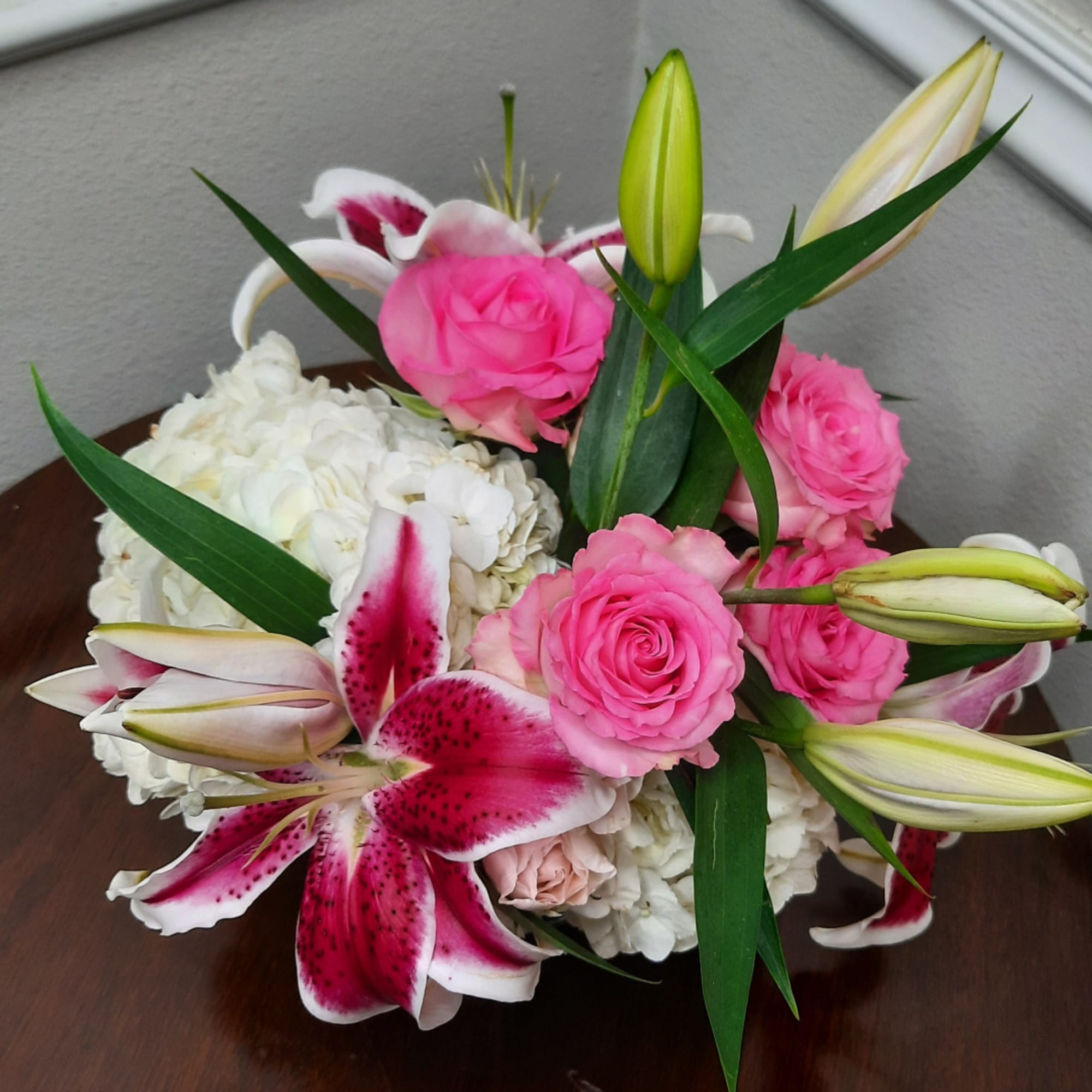 Pink roses and white lilies arranged with white hydrangeas in a low bouquet
