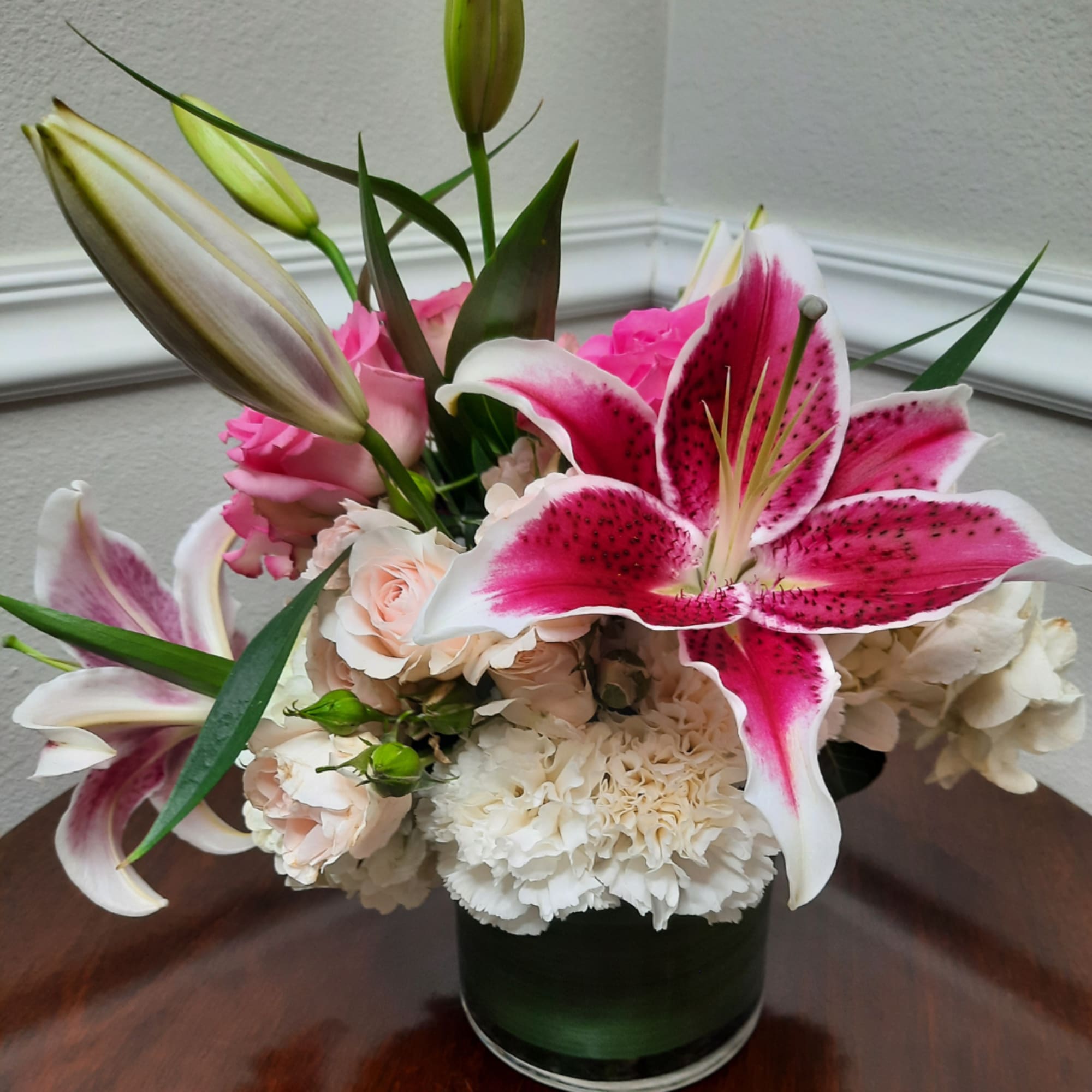 Pink and white lilies with roses and carnations in a glass vase