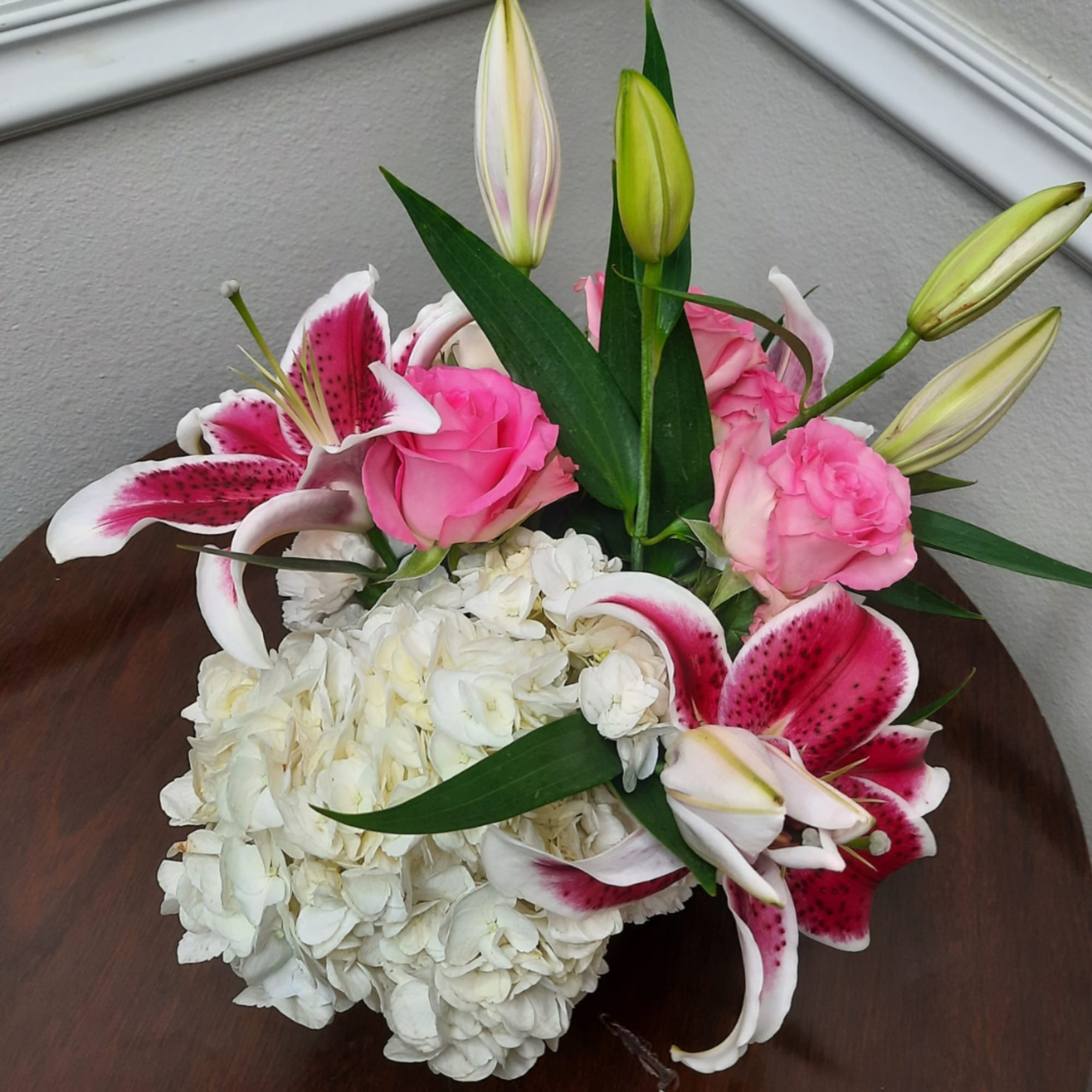 Pink roses and white lilies arranged with white hydrangeas in a vase