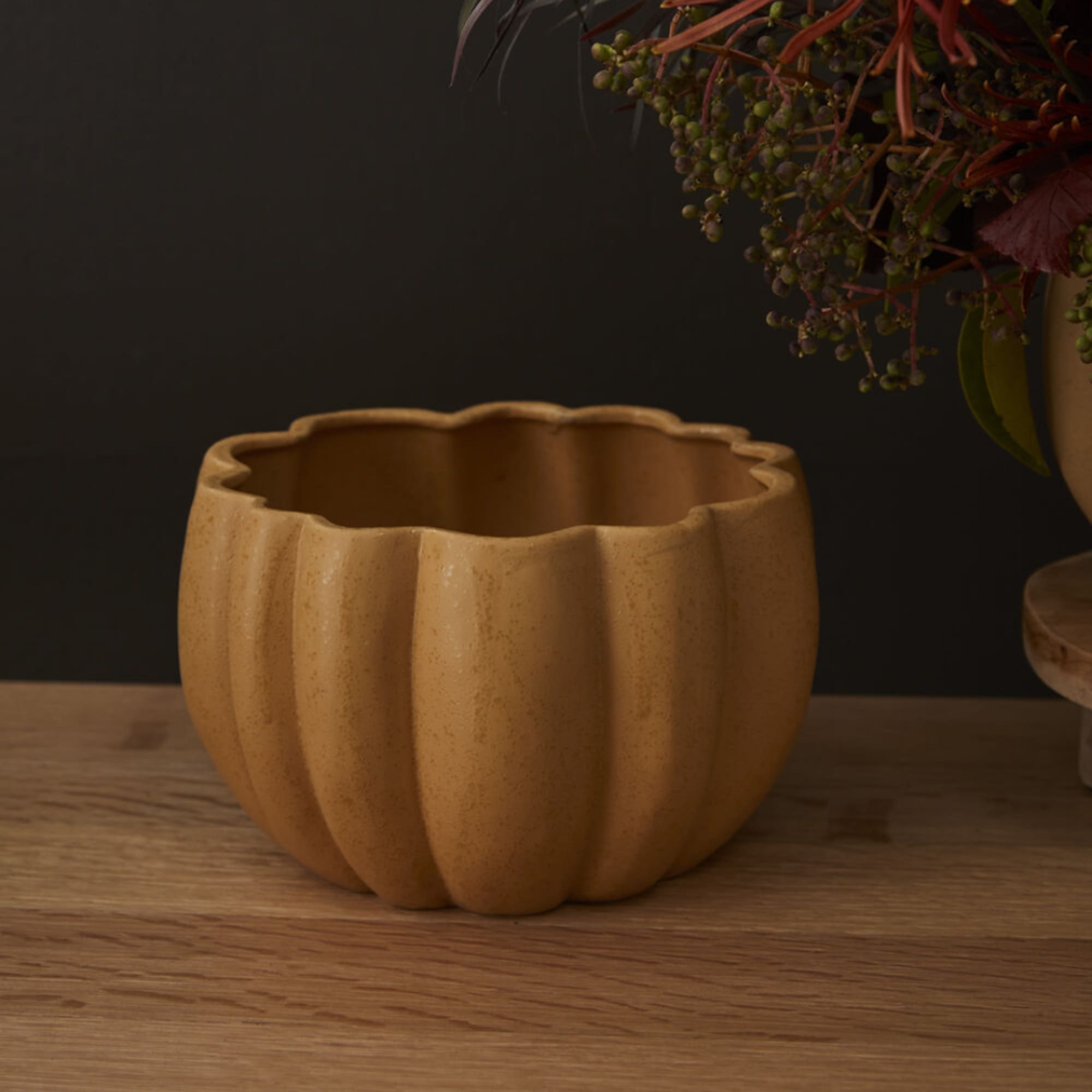 Empty pumpkin-shaped ceramic planter on a wooden surface