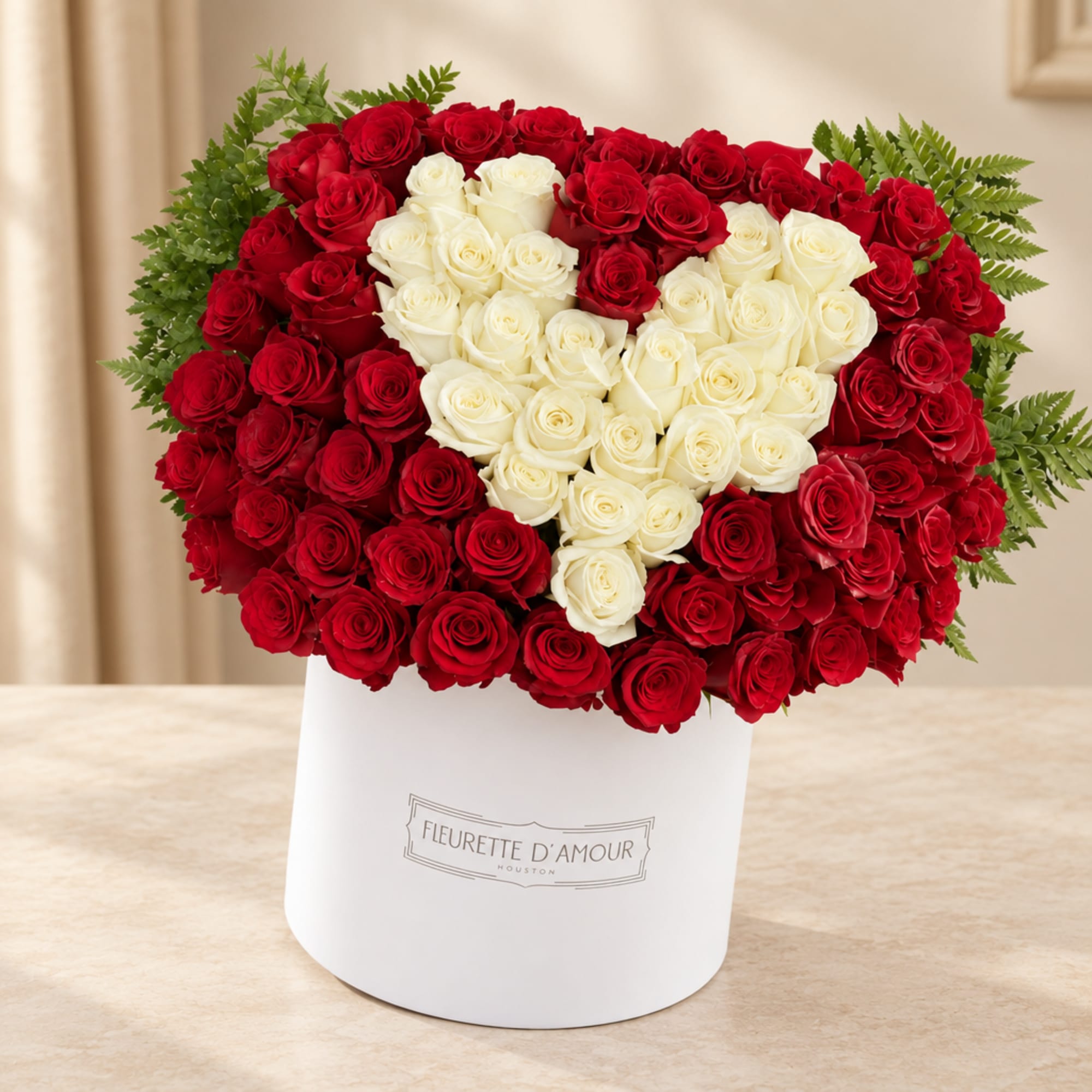 Red and white roses arranged in a heart shape in a white box
