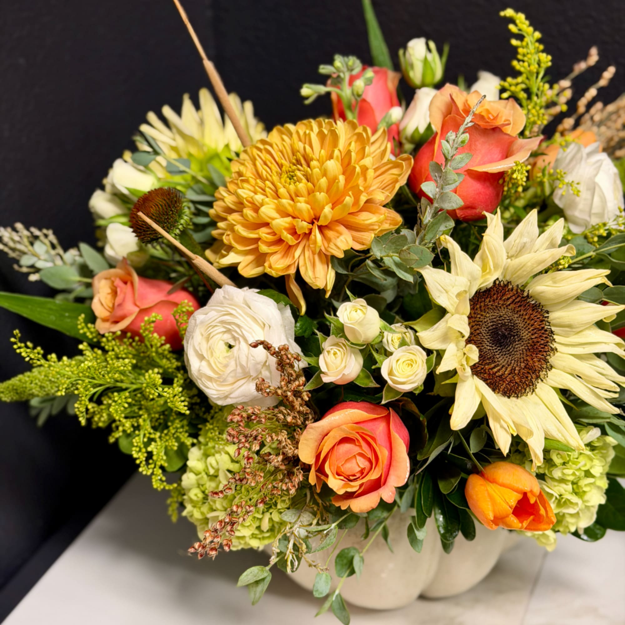 Mixed bouquet with sunflowers, roses, and white blooms in a vase