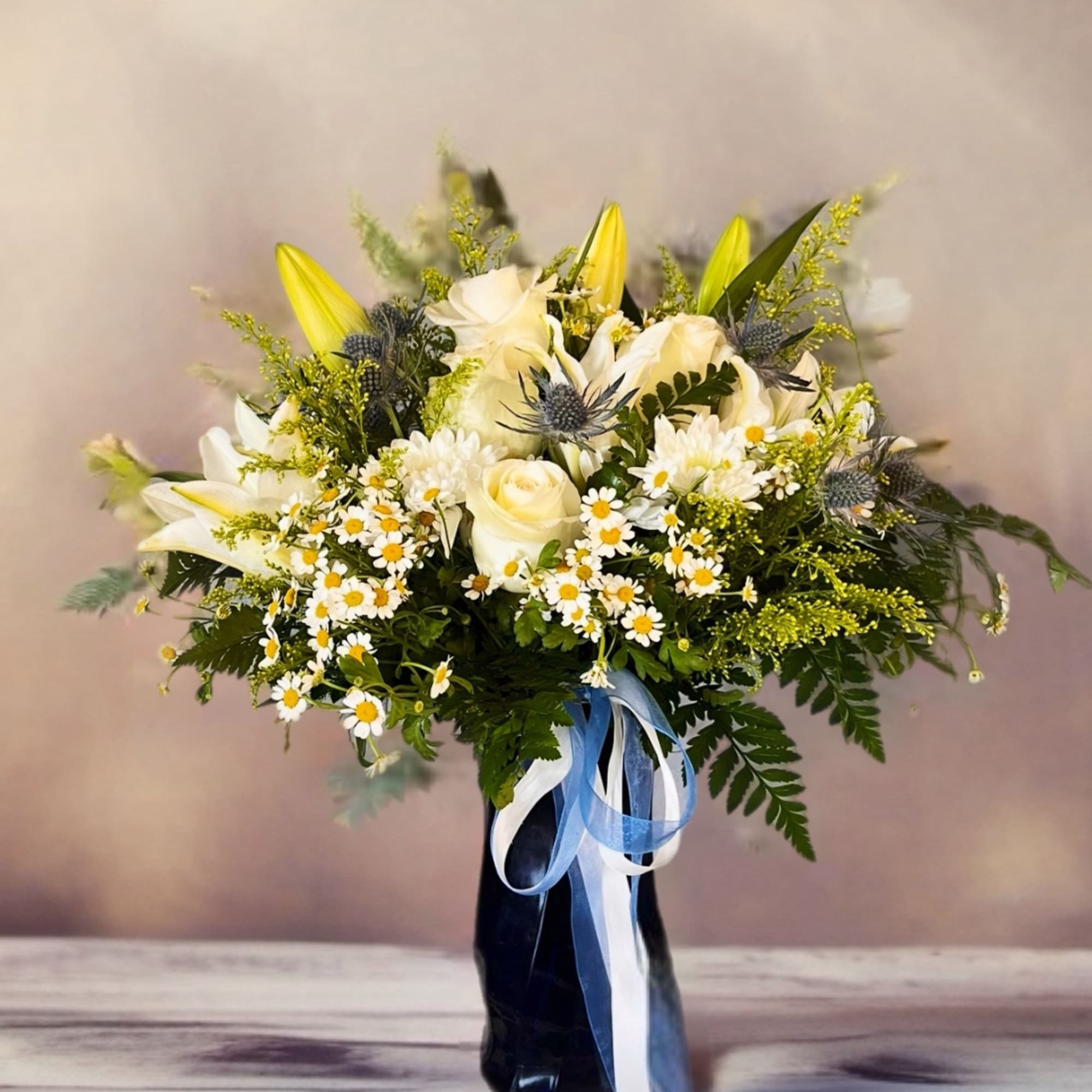 White and yellow flower bouquet in a dark vase with blue ribbon