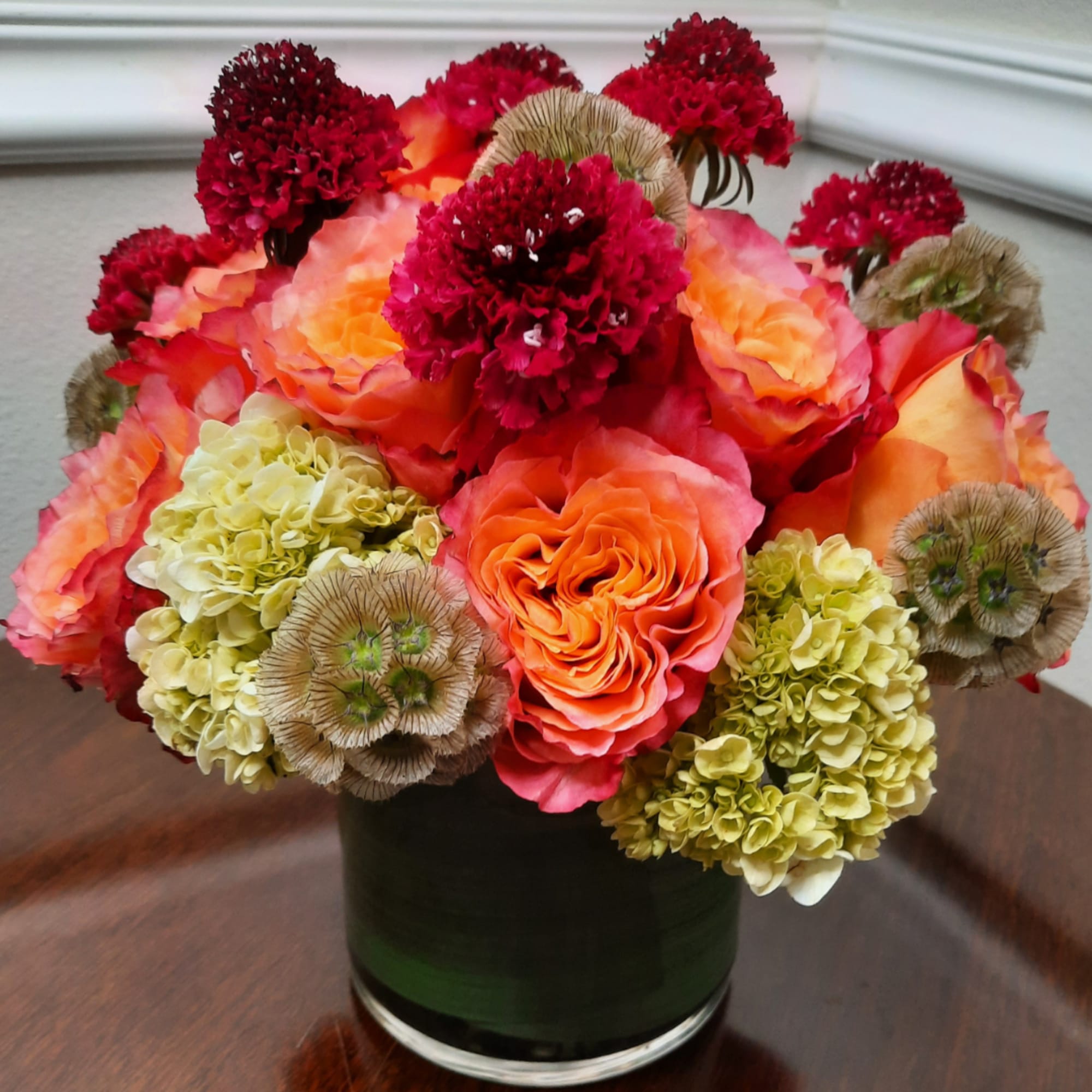 Orange roses and red carnations in a dark glass vase