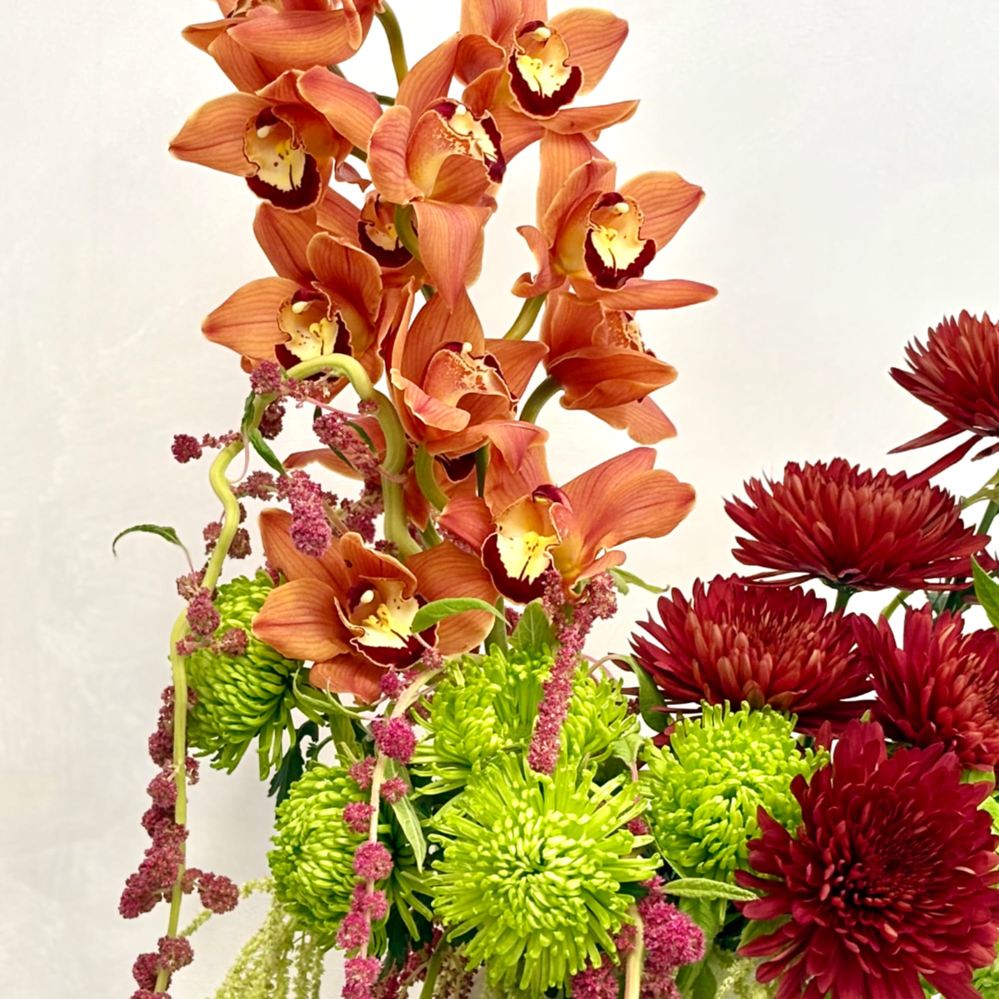 Orange orchids with green and deep red chrysanthemums