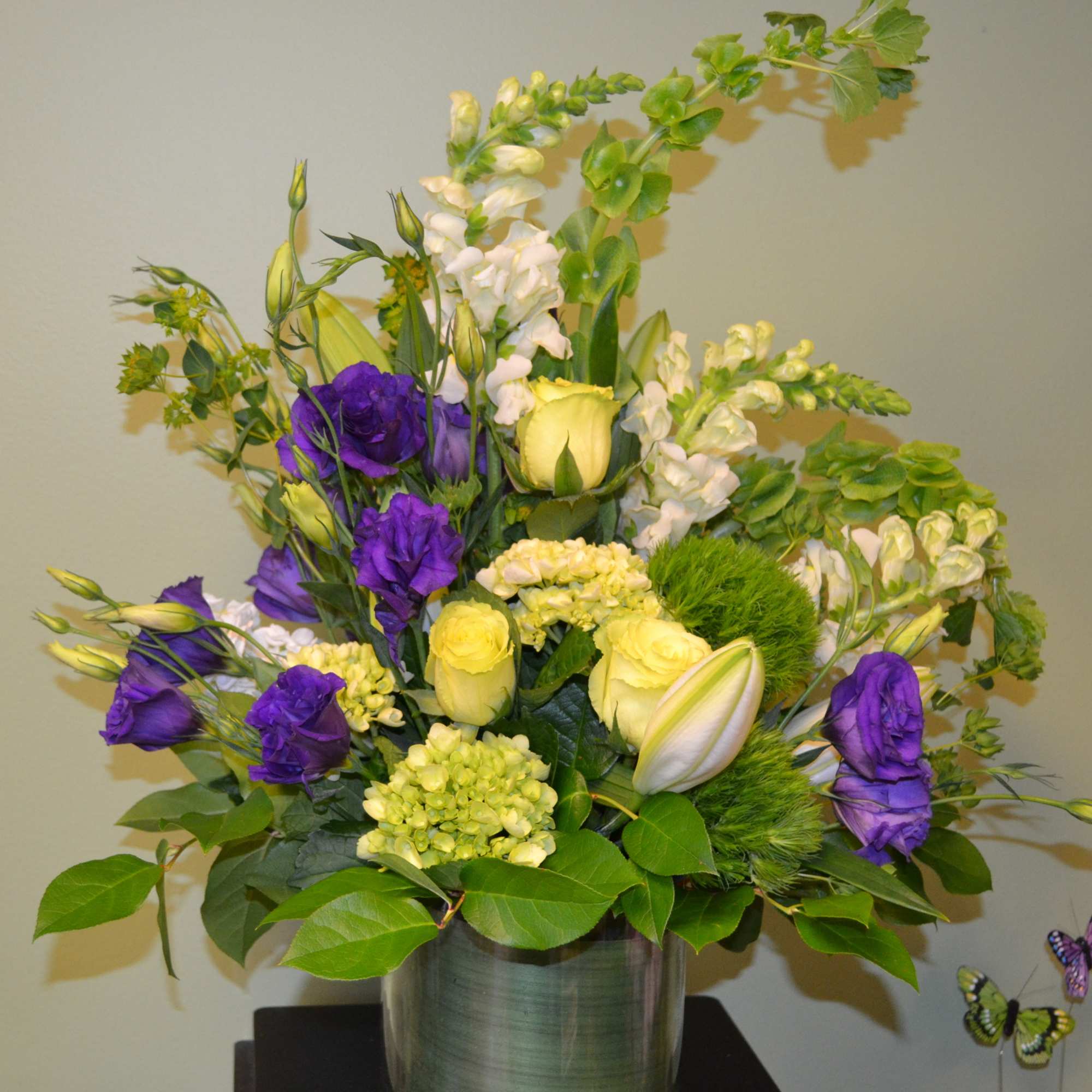 Purple and yellow floral arrangement in a metal vase
