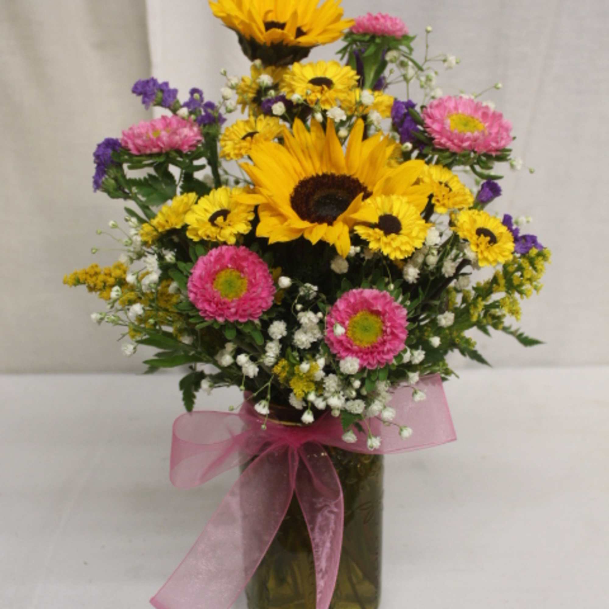 Mixed bouquet with sunflowers and pink daisies in a glass vase