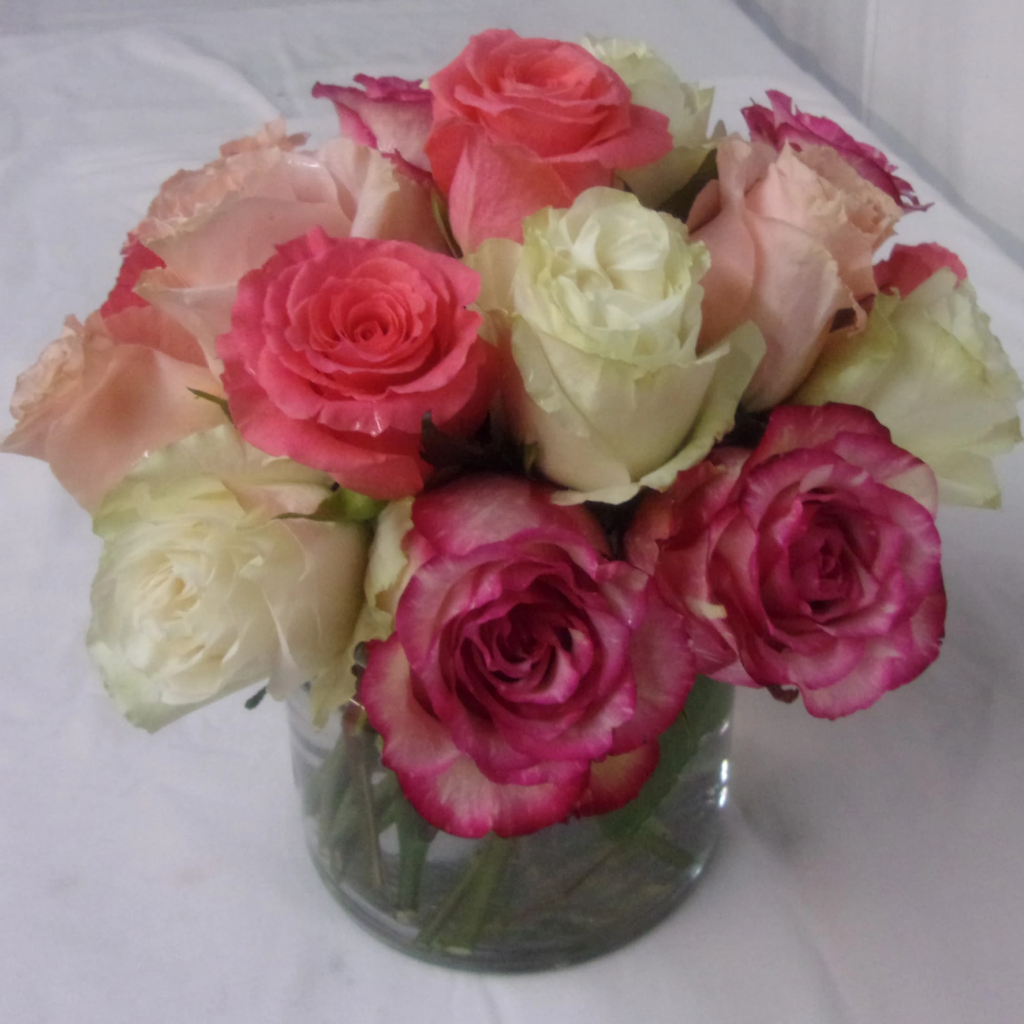 Bouquet of pink, cream, and peach roses in a glass vase