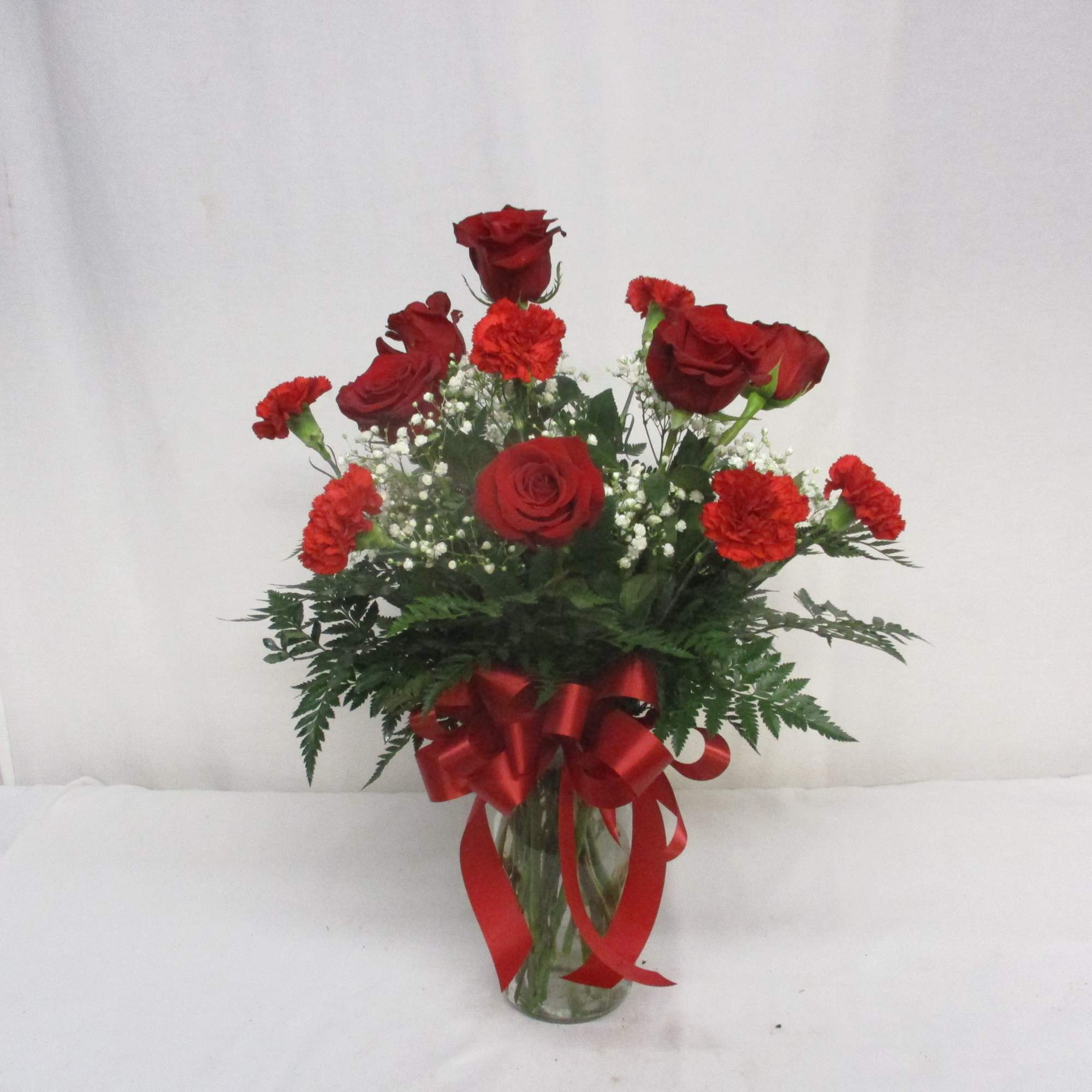 Red roses and carnations in a glass vase with a red ribbon