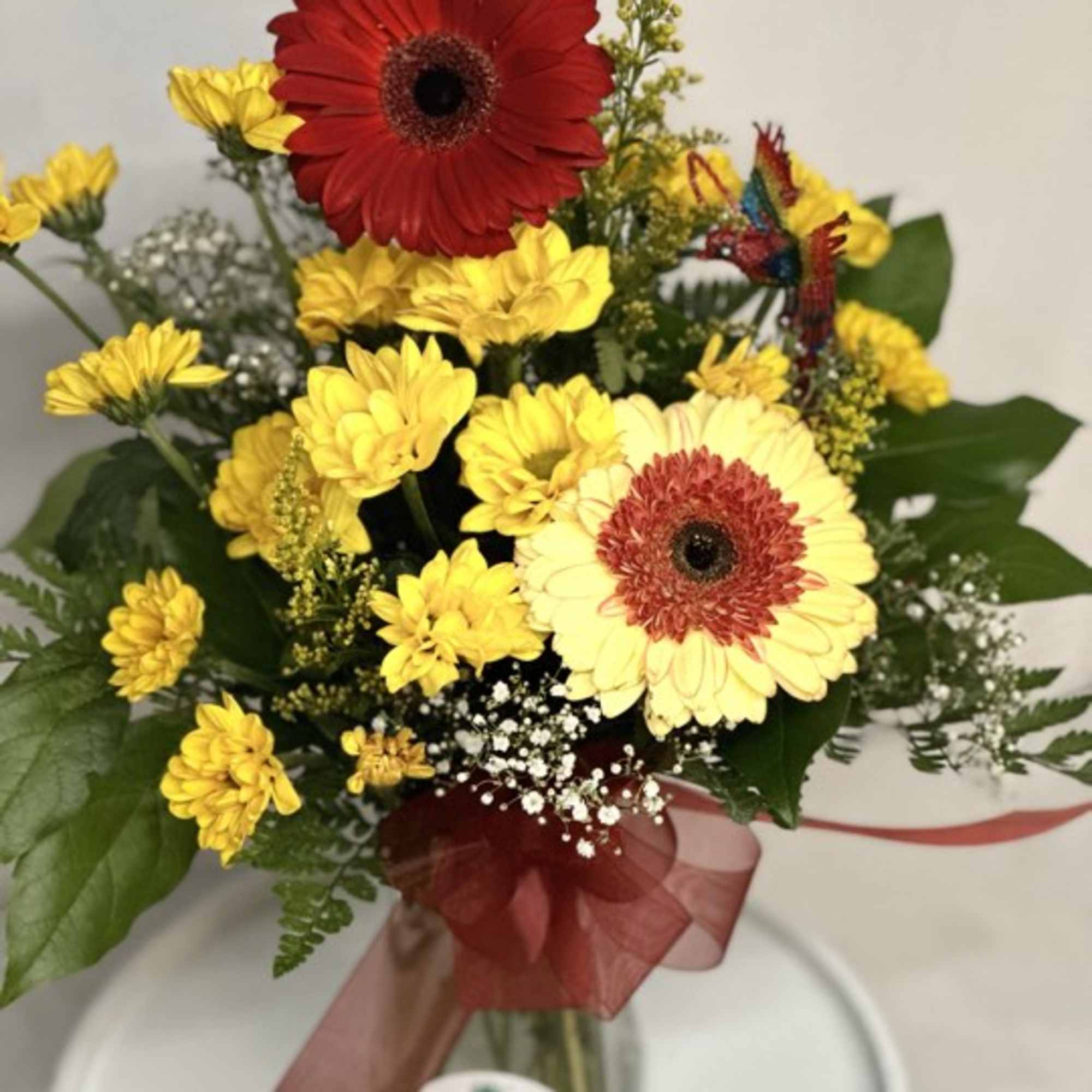 Bouquet of red and yellow gerbera daisies in a glass vase with a ribbon