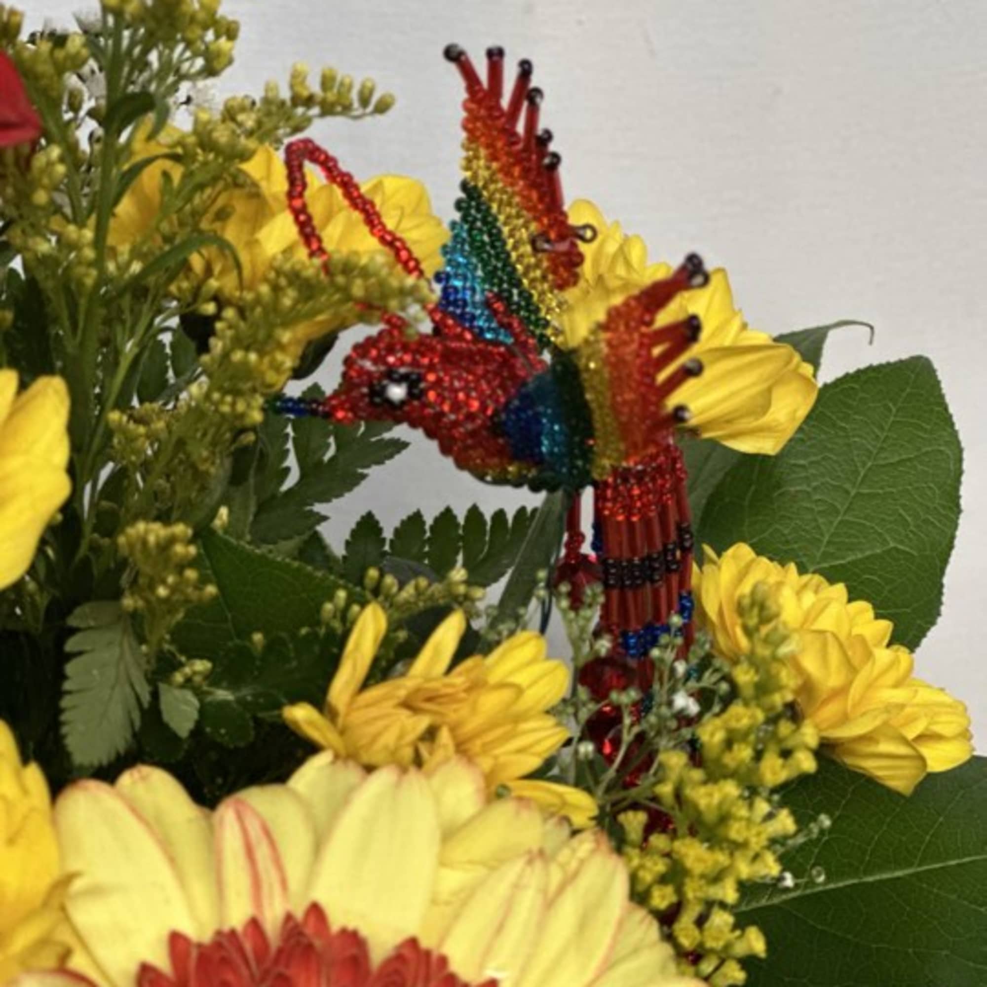 Yellow and red flowers with a colorful beaded hummingbird decoration