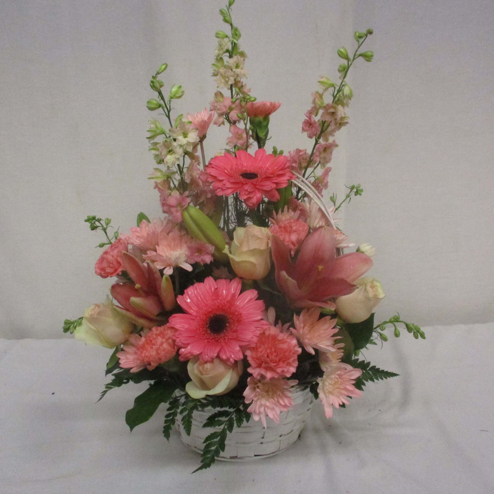 Pink mixed flower arrangement in a white basket