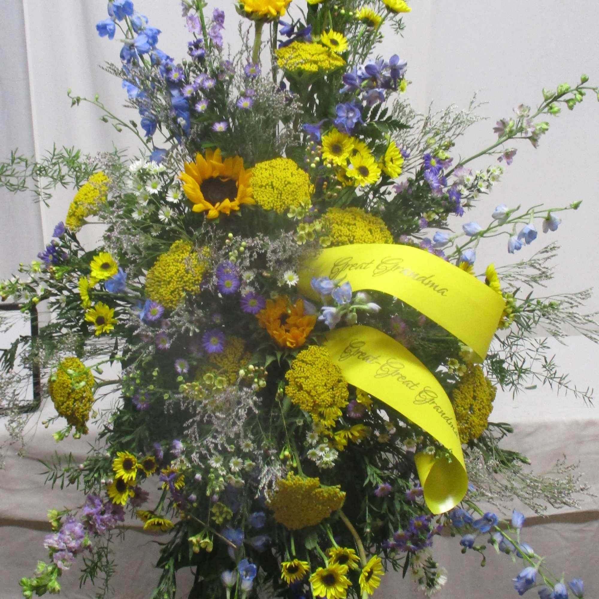 Tall floral spray with yellow and blue flowers on a stand