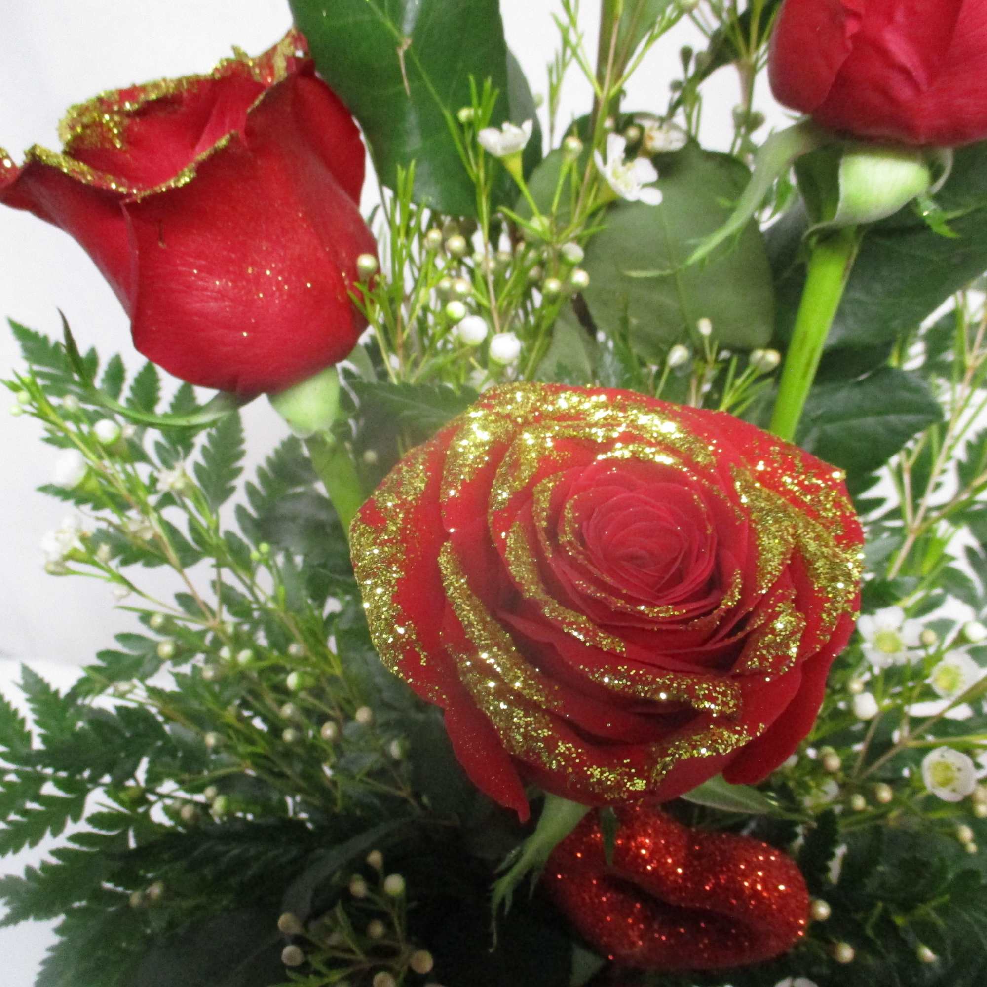Red roses with gold glitter accents and small white filler flowers