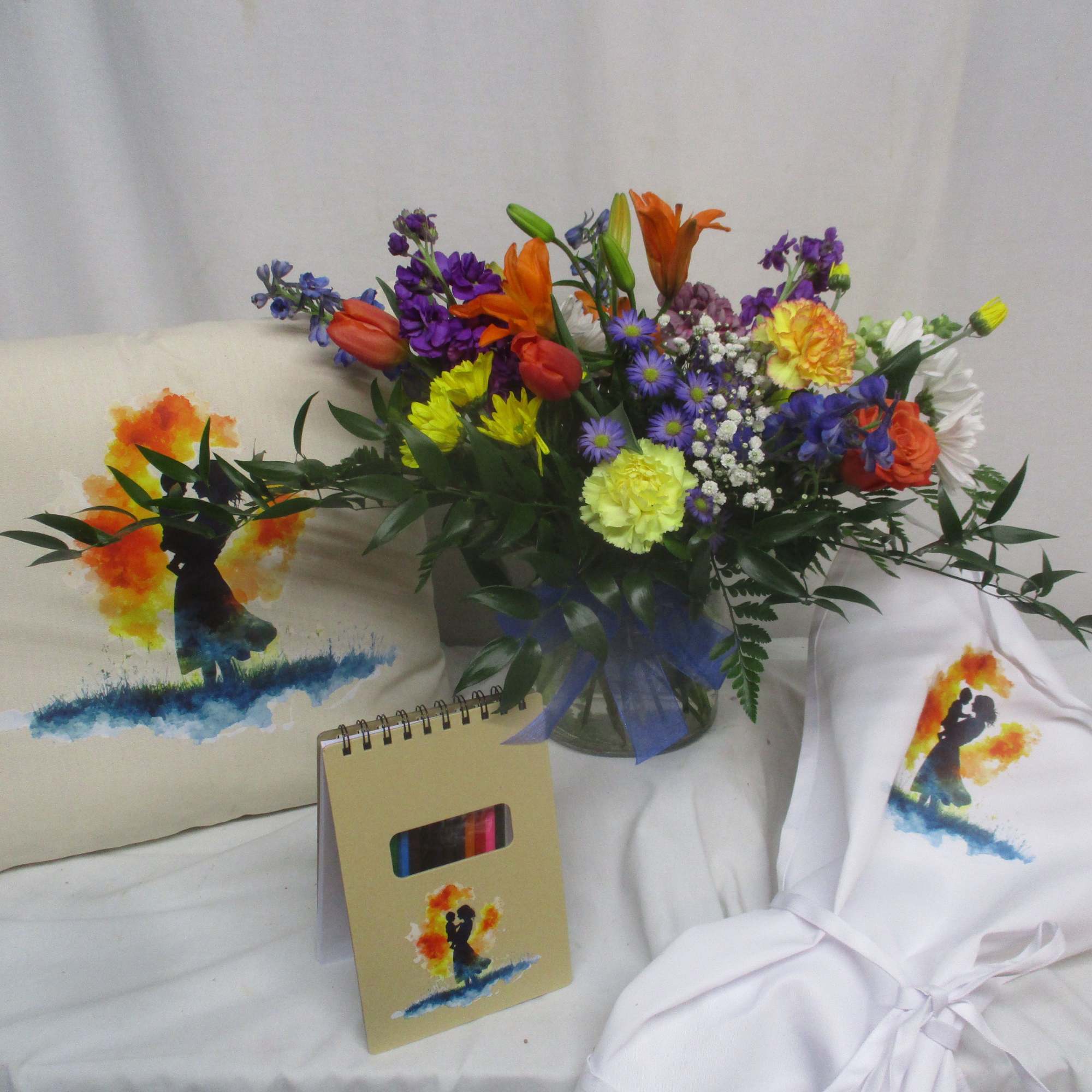 Bright, multicolored tulips, carnations, daisies and lilies tumble from a clear glass