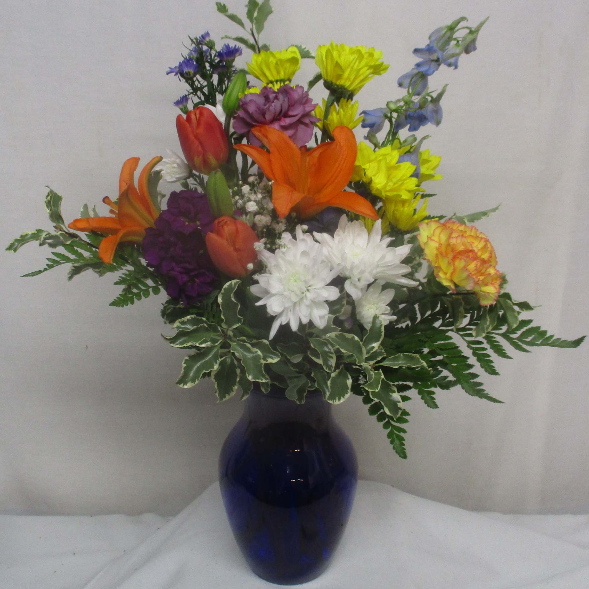 Bright, garden-fresh blooms in a glossy blue glass vase create a joyful, photo 2 of 3