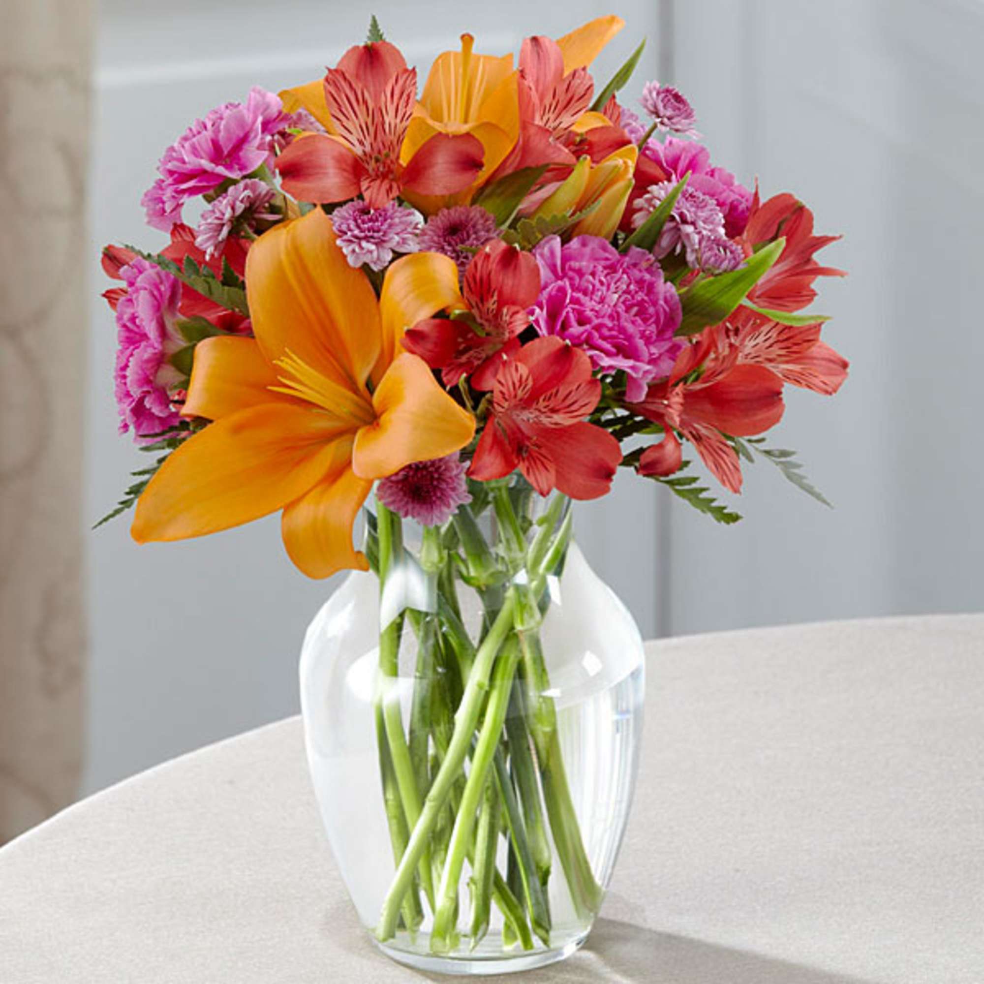 Colorful bouquet of lilies, alstroemeria, and carnations in a clear glass vase