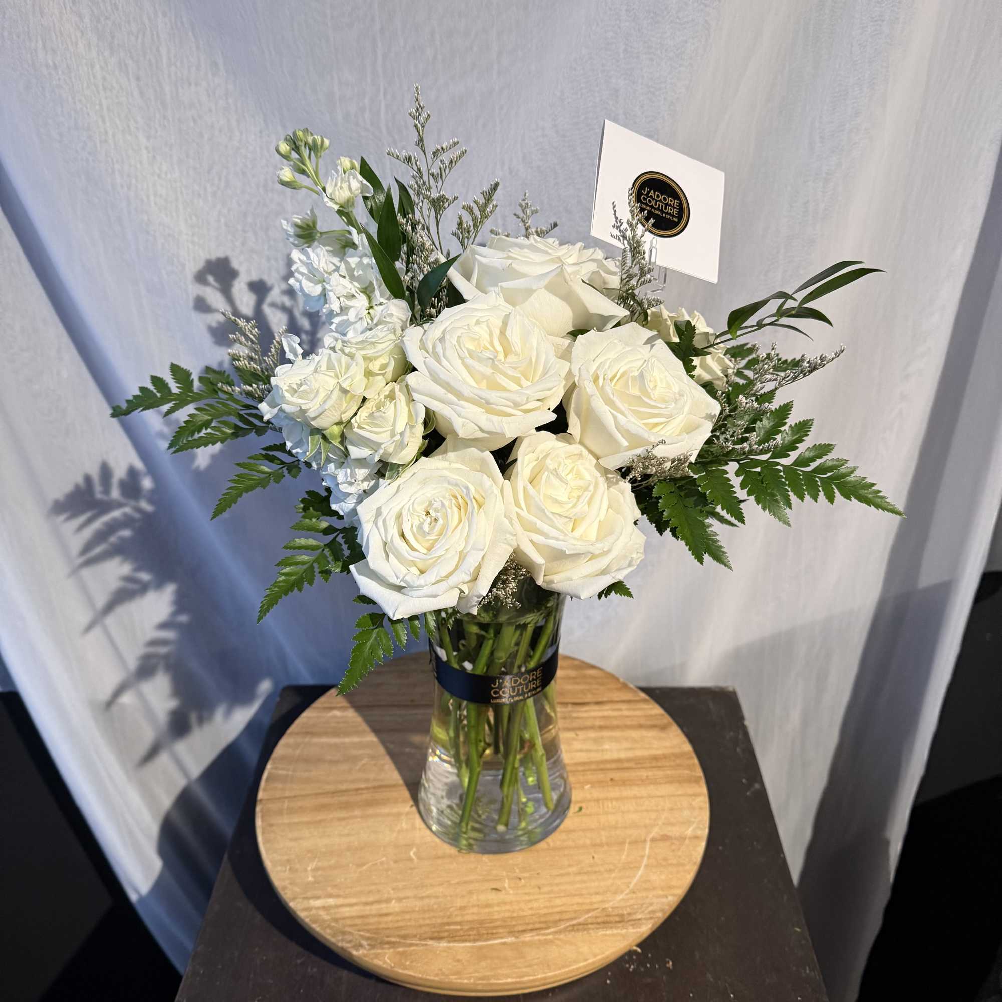 In season white dendrobium orchid, white, spray rose filled with ti-leaf and