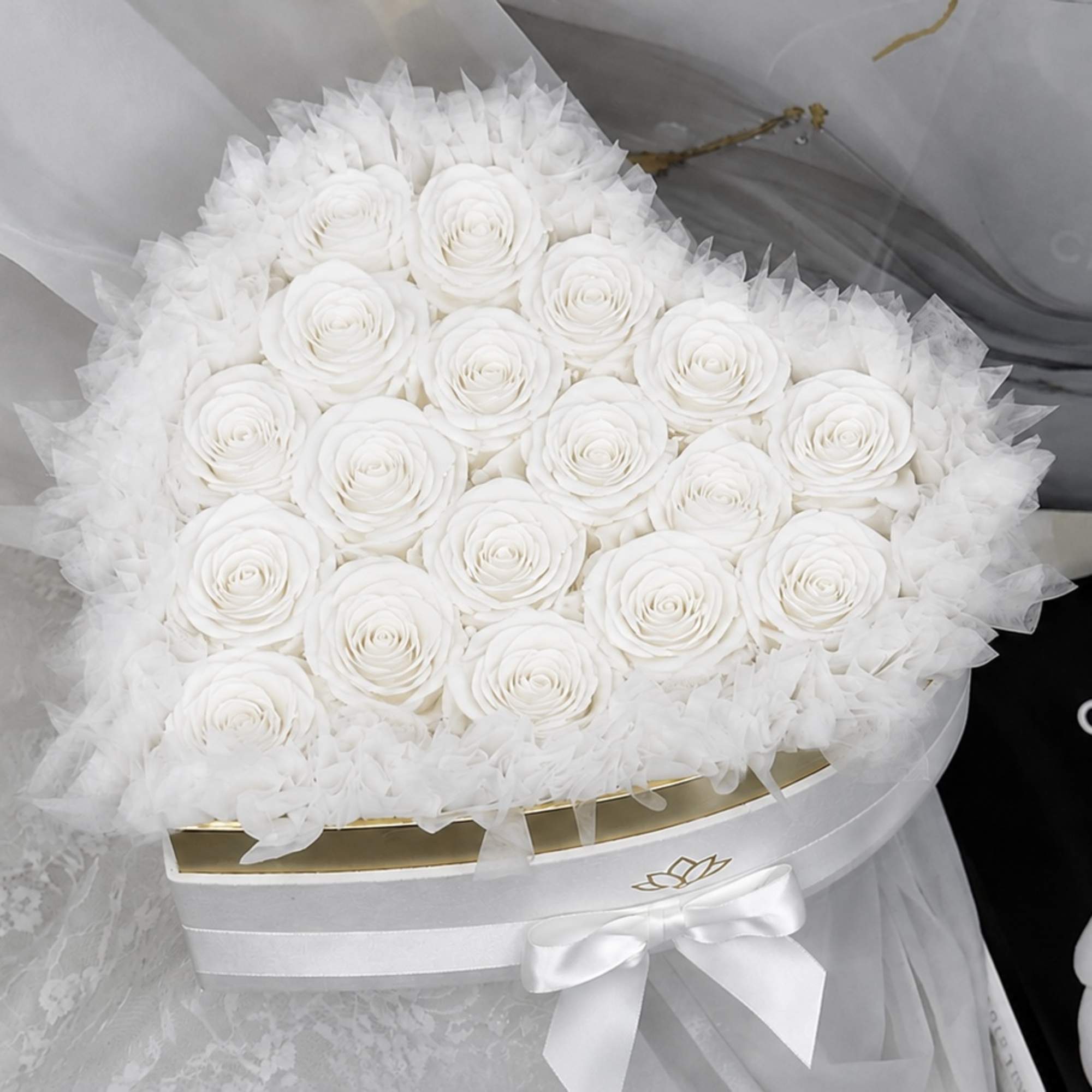 Round bouquet of white roses wrapped in sheer white tulle