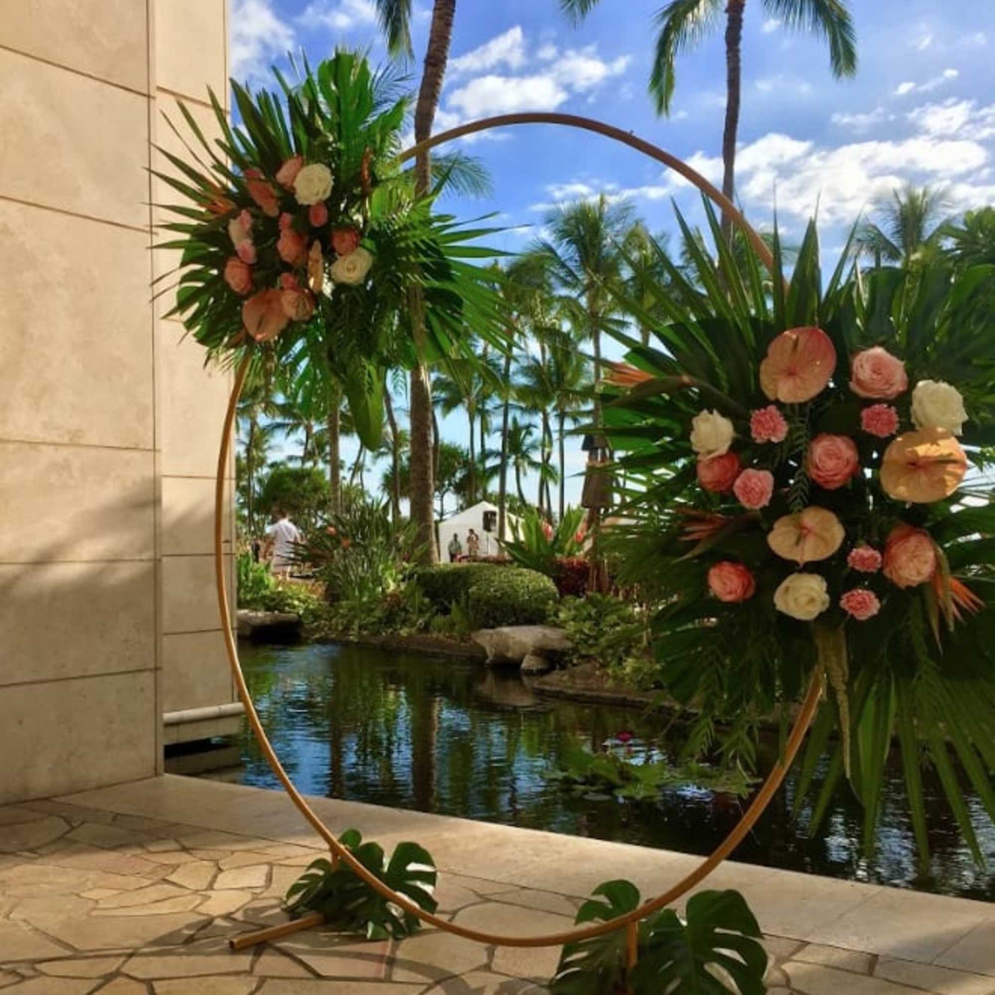 Two floral arrangements on a circular stand beside a tropical pool