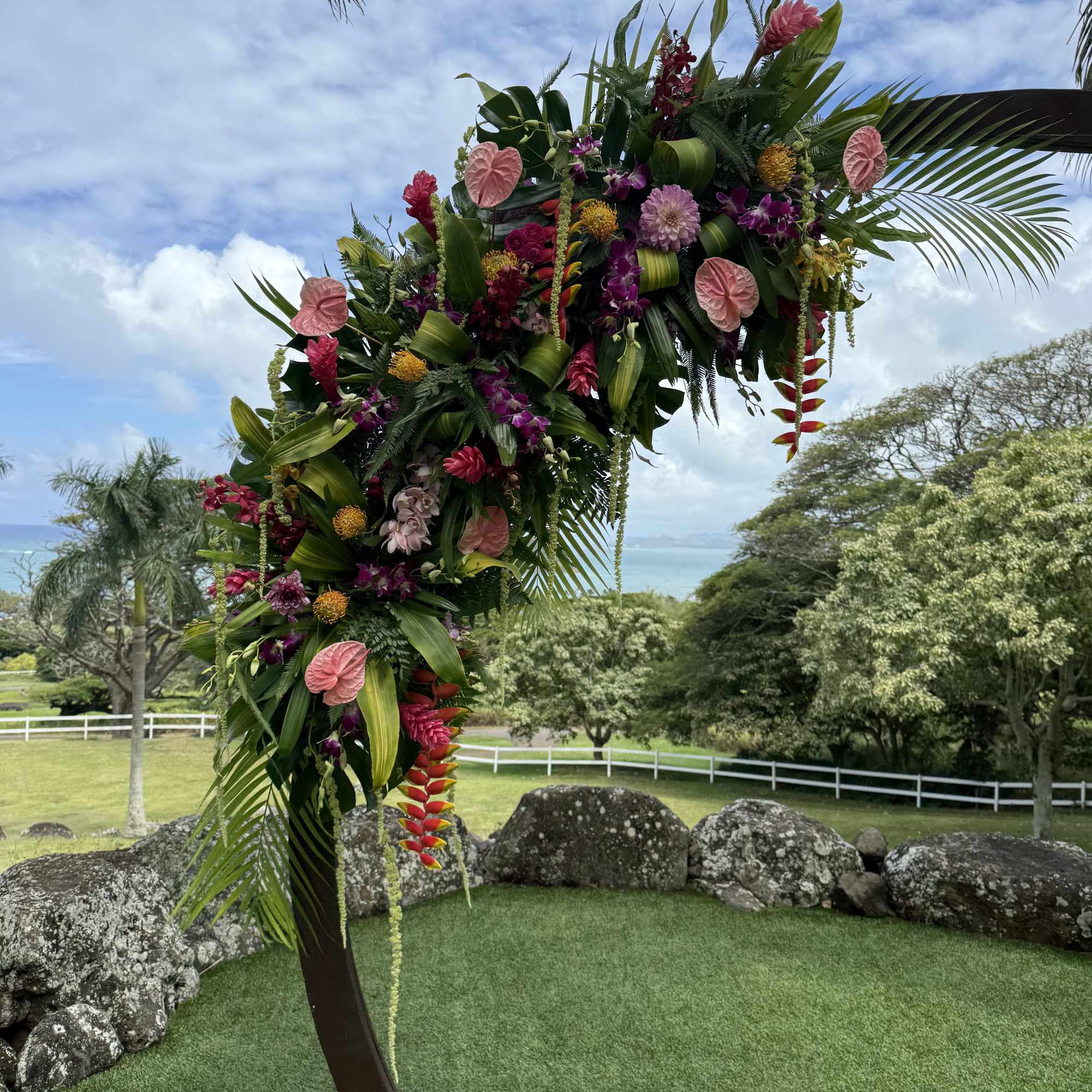Two large tropical flower designs adorning a circular wedding arch. Circular arch, photo 2 of 3
