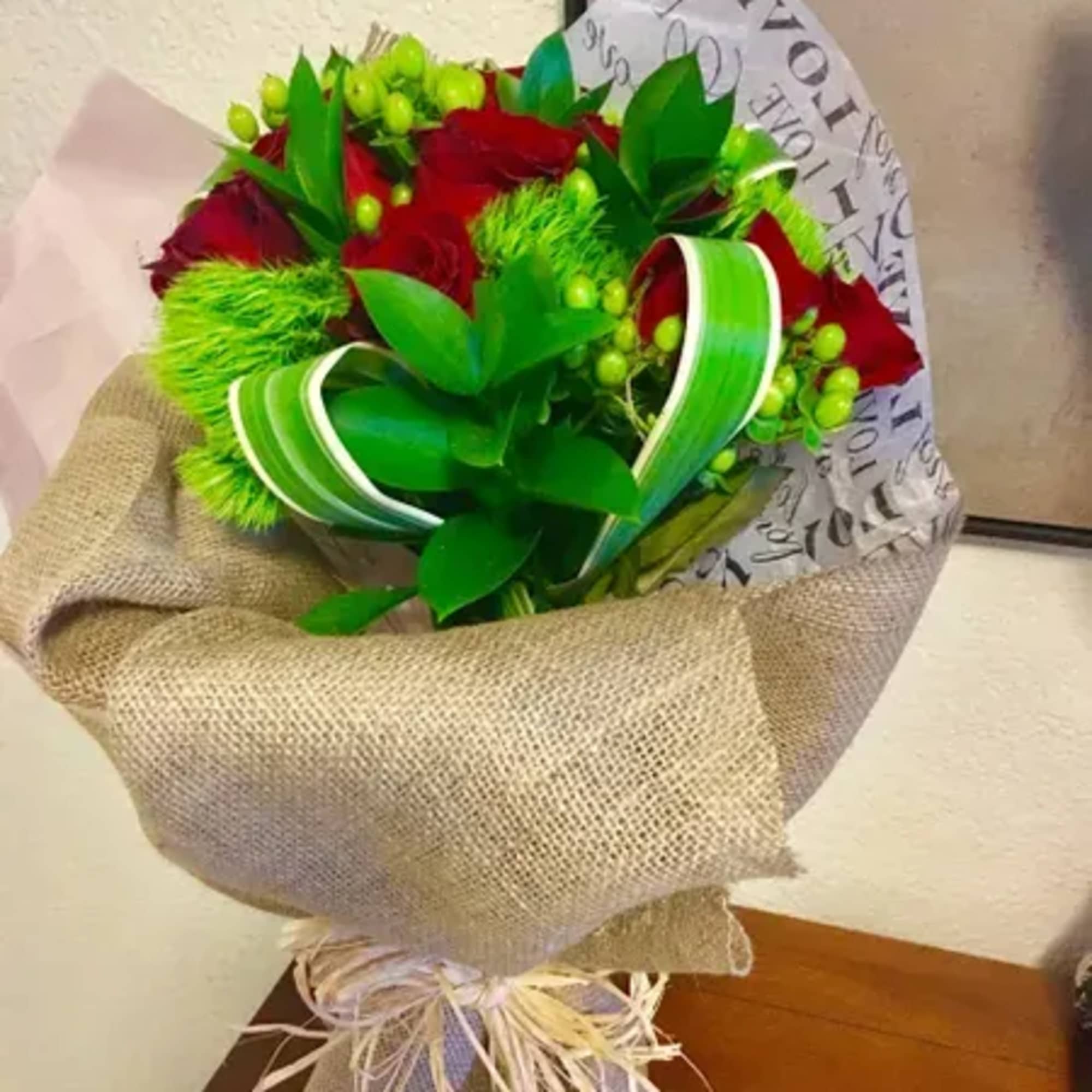 Bouquet of red roses wrapped in burlap with green ribbon
