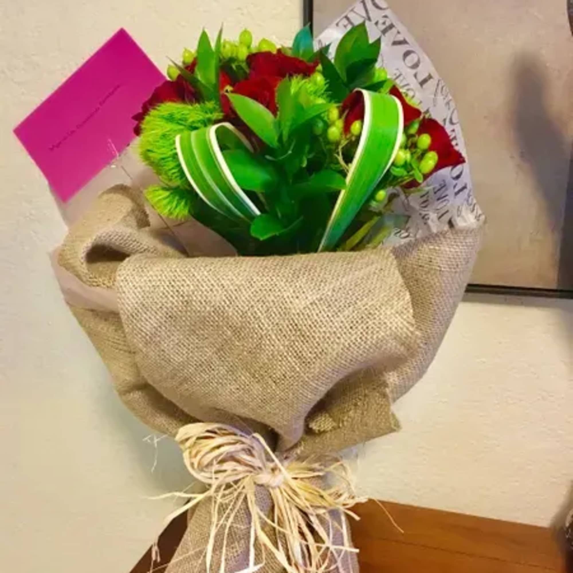 Bouquet of red roses wrapped in burlap with green ribbon, photo 2 of 3