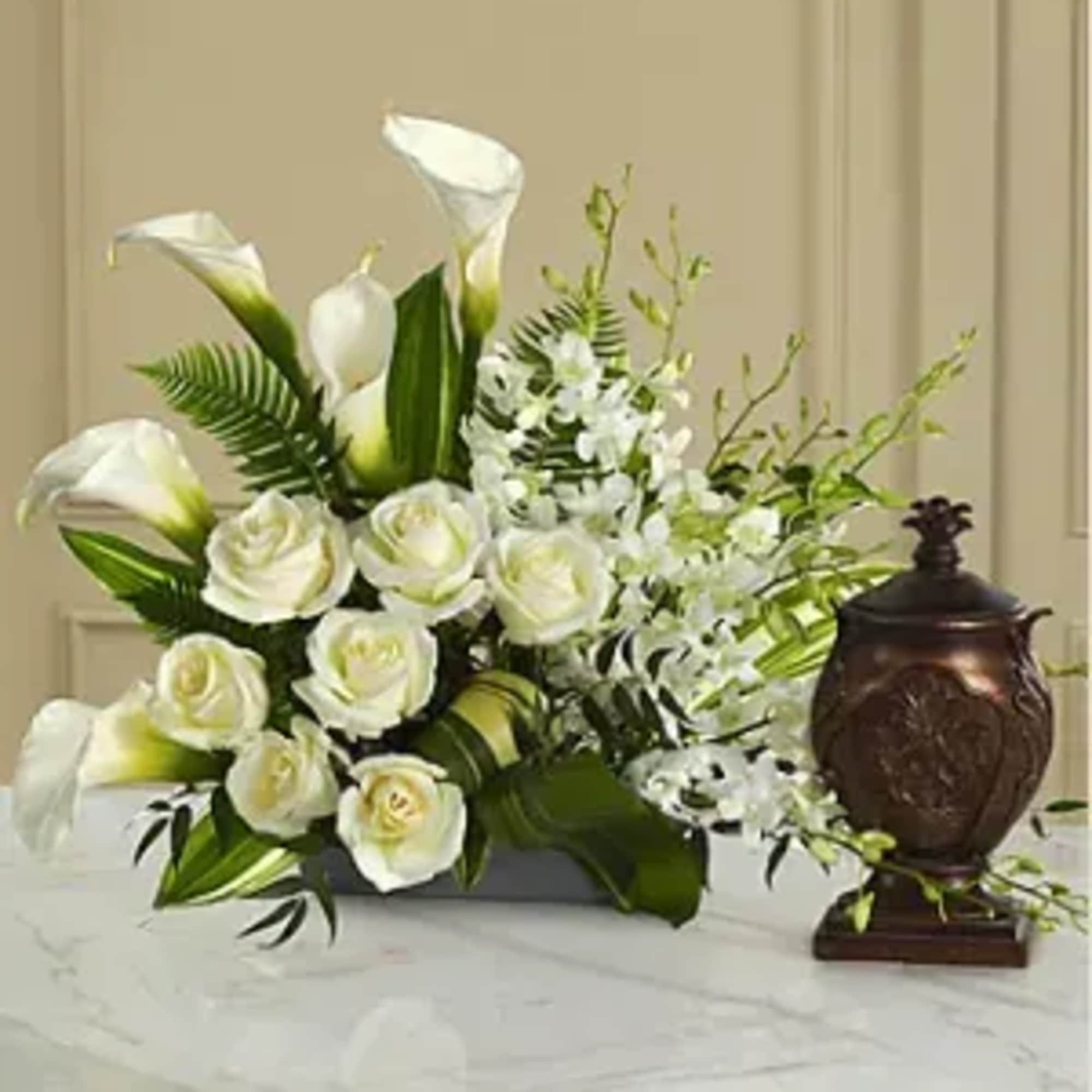 White roses and calla lilies arranged with greenery in a low container