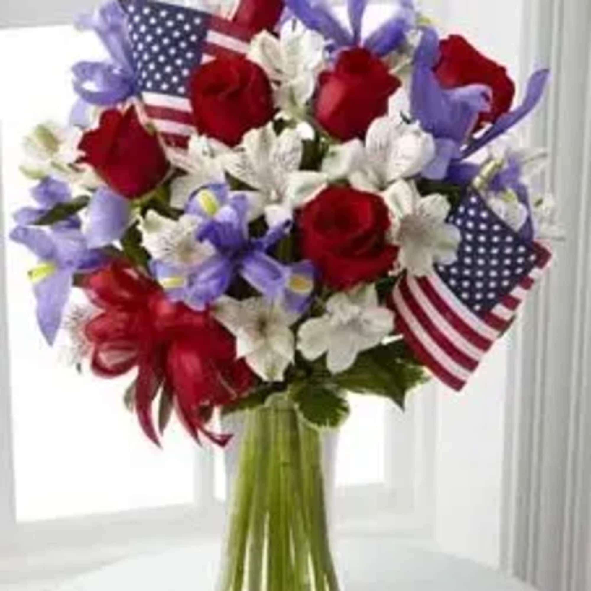 Bouquet of red roses and white flowers with small American flags in a glass vase