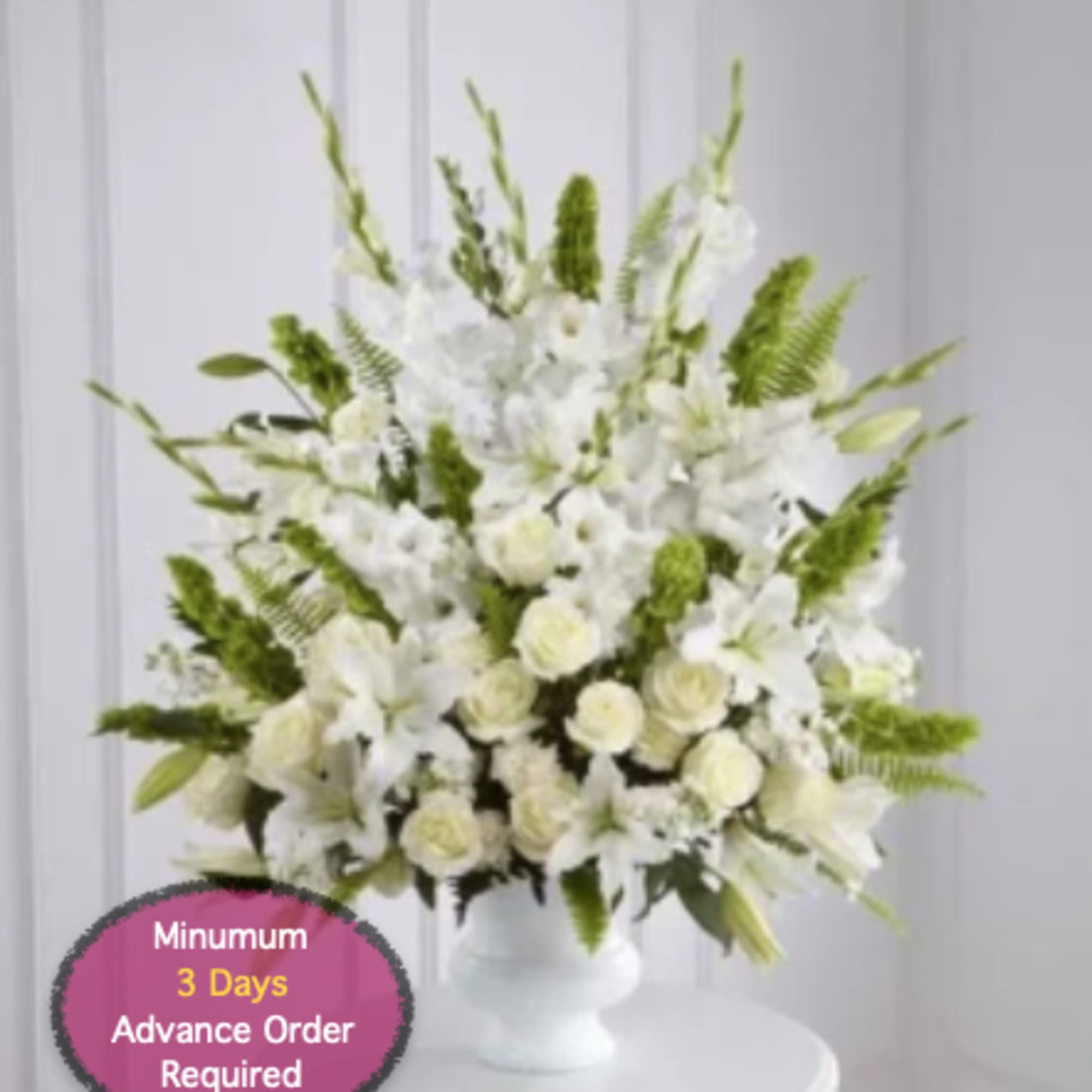 White floral arrangement in a white vase with green accents