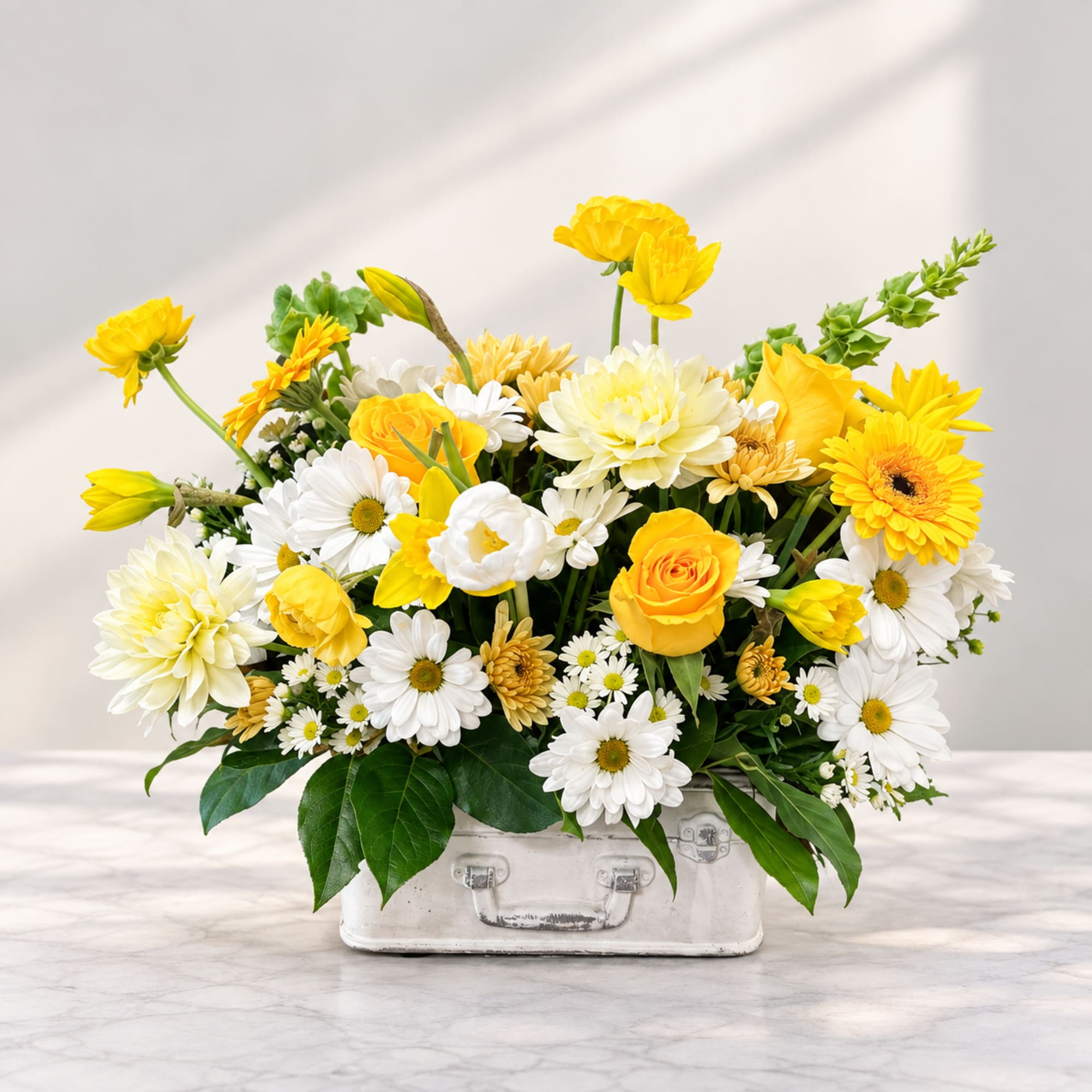 Yellow and white mixed flower arrangement in a white container
