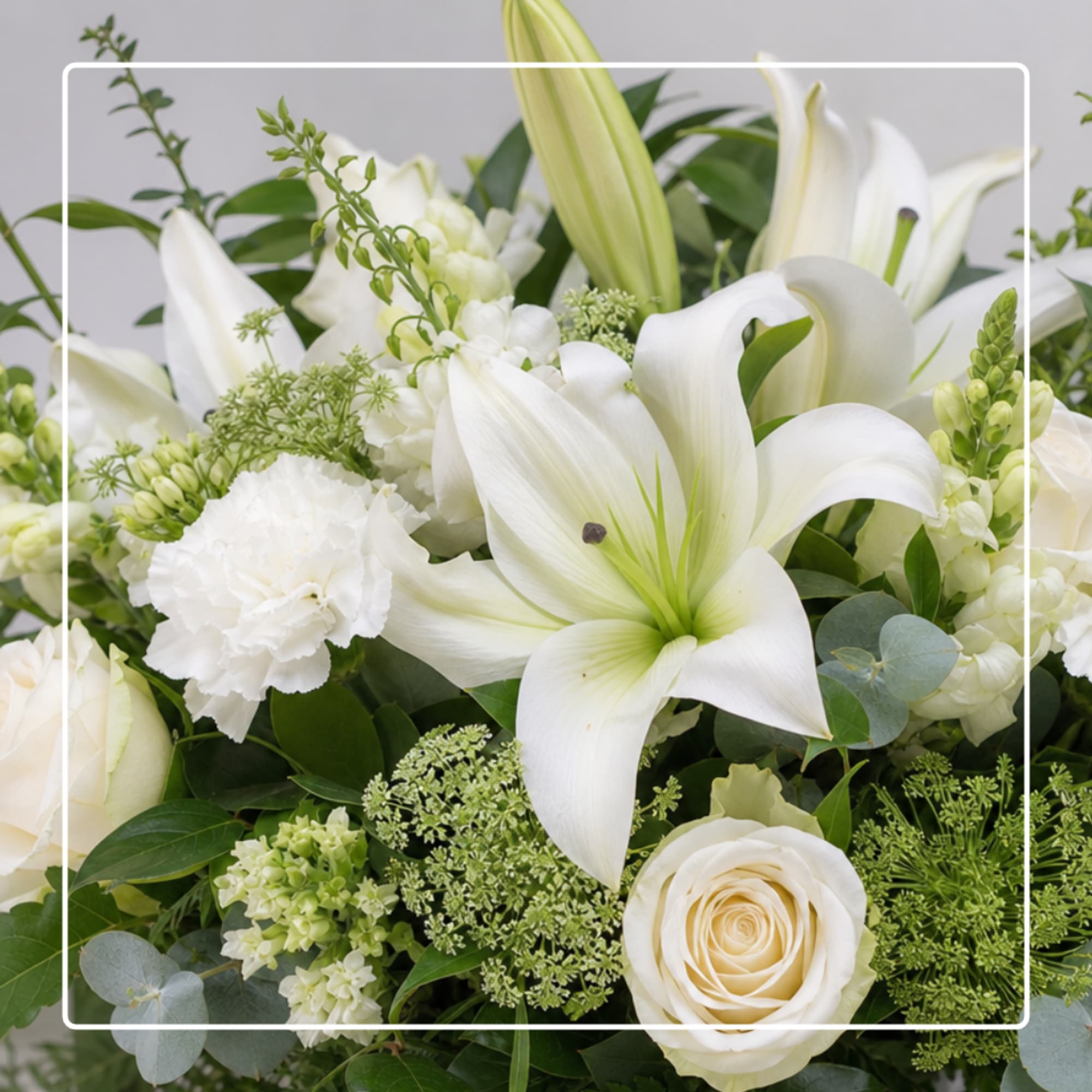 White lilies and roses arranged with green filler in a low bouquet