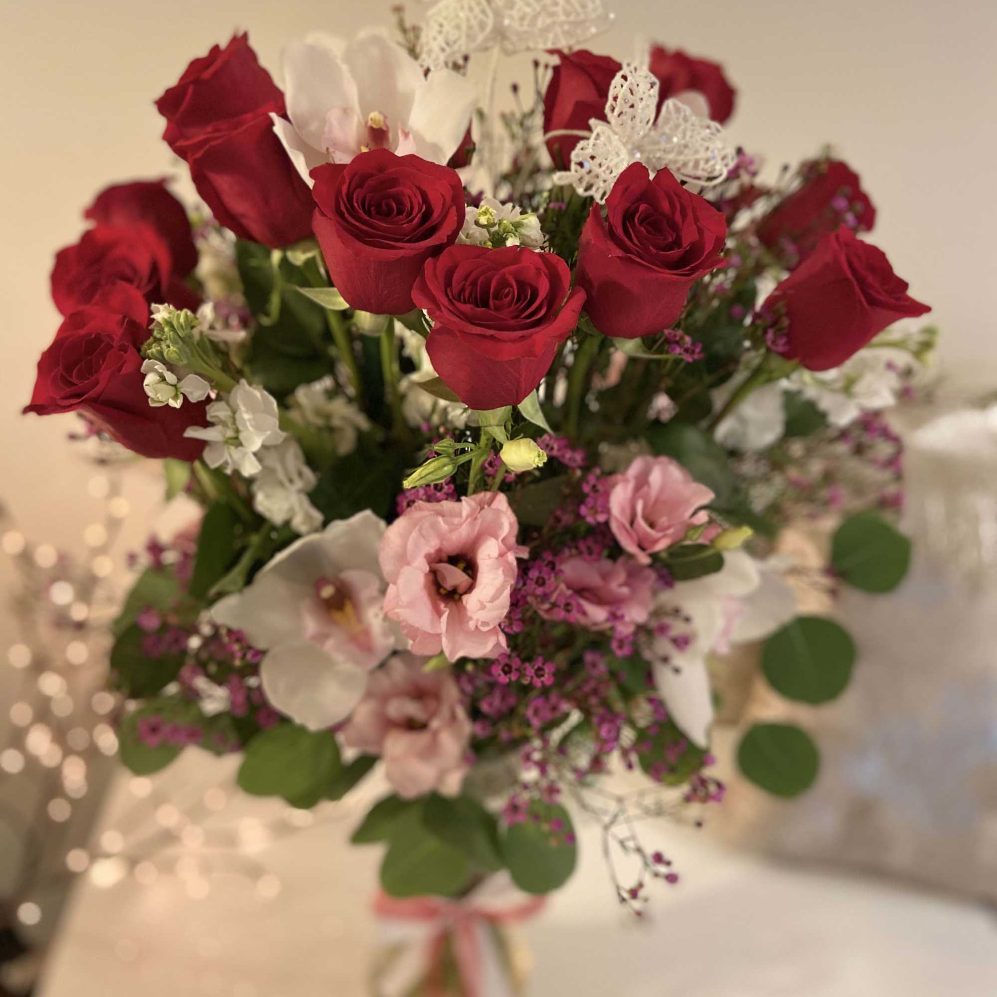 Bouquet of red roses and pink blooms with white butterfly accents