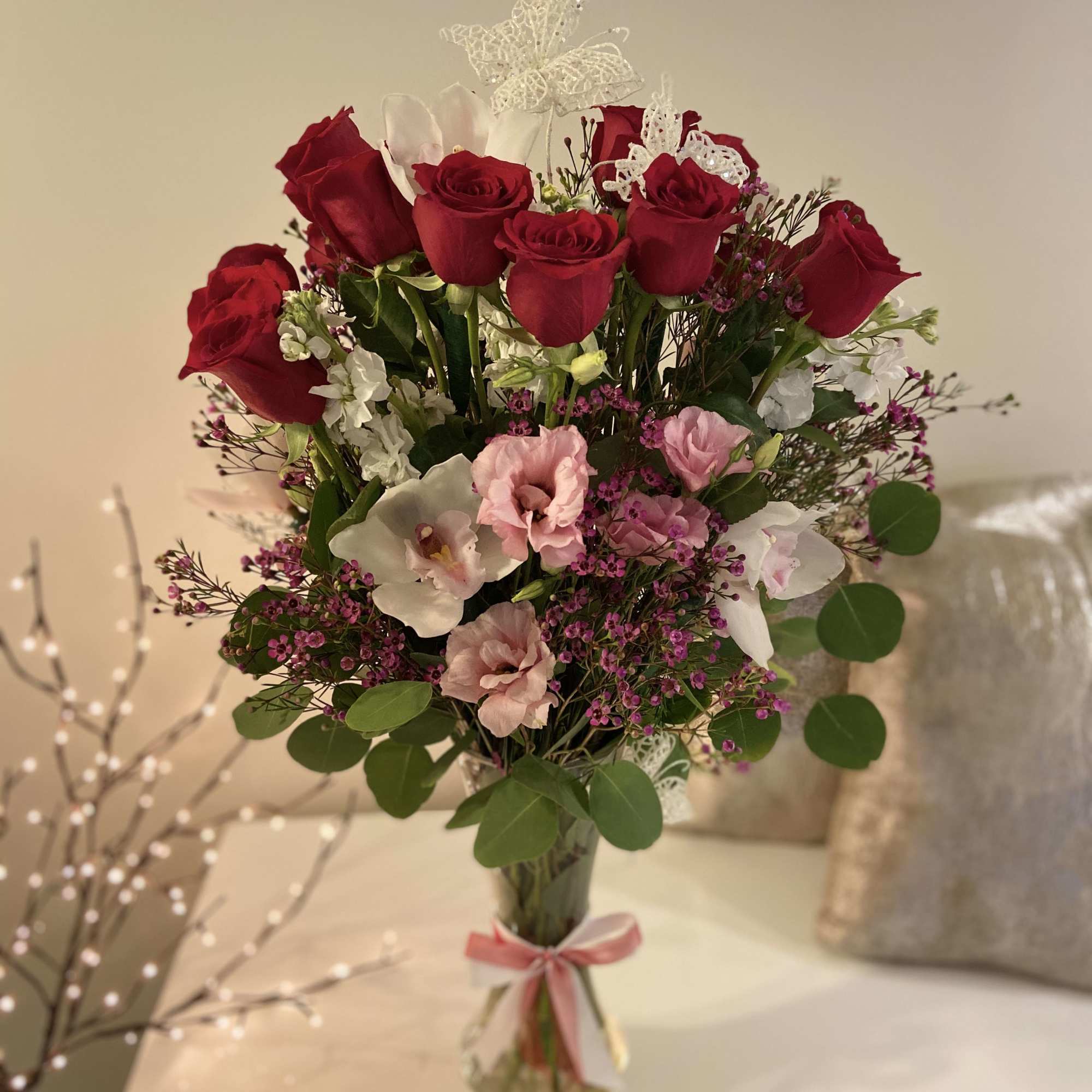 Bouquet of red roses and pink flowers in a glass vase with a ribbon