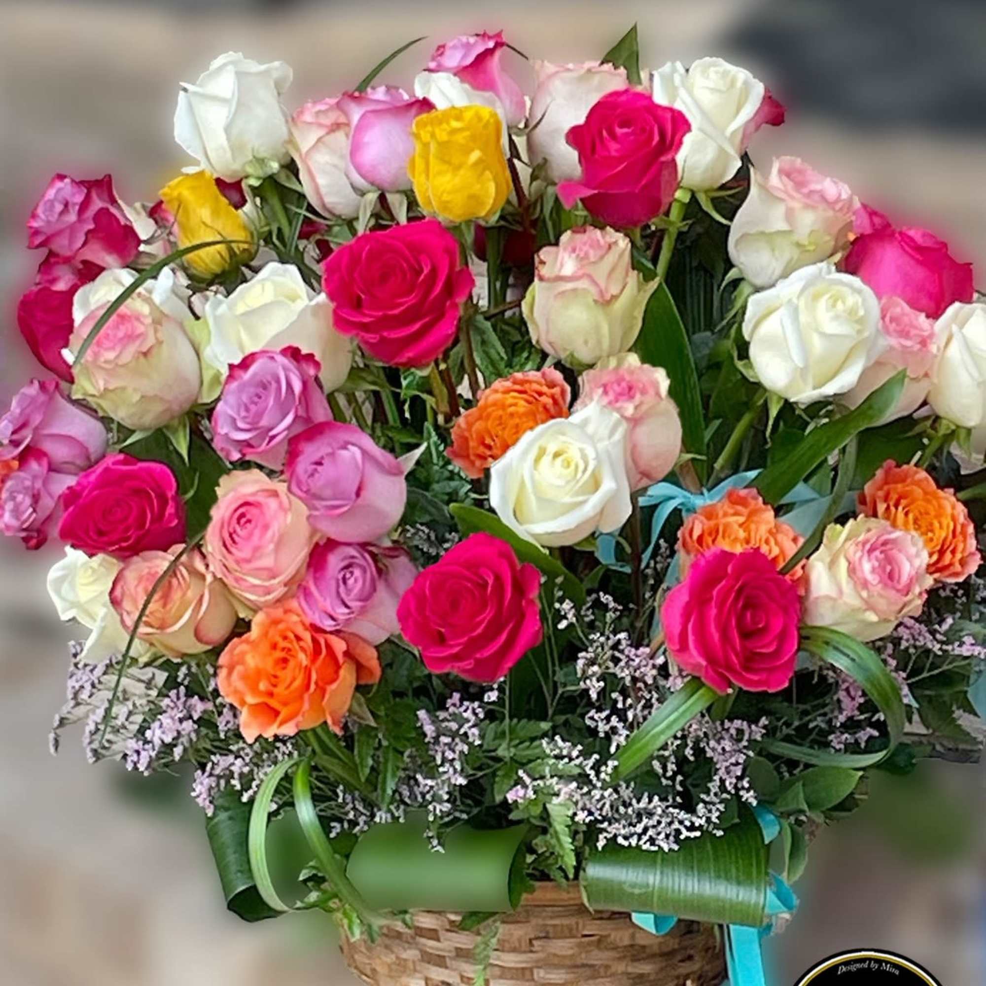 Basket arrangement of bright pink, white, yellow, and orange roses with filler flowers