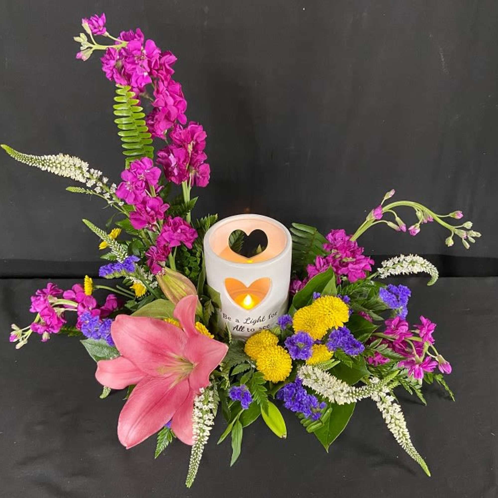 Pink lily arrangement with a lit candle centerpiece