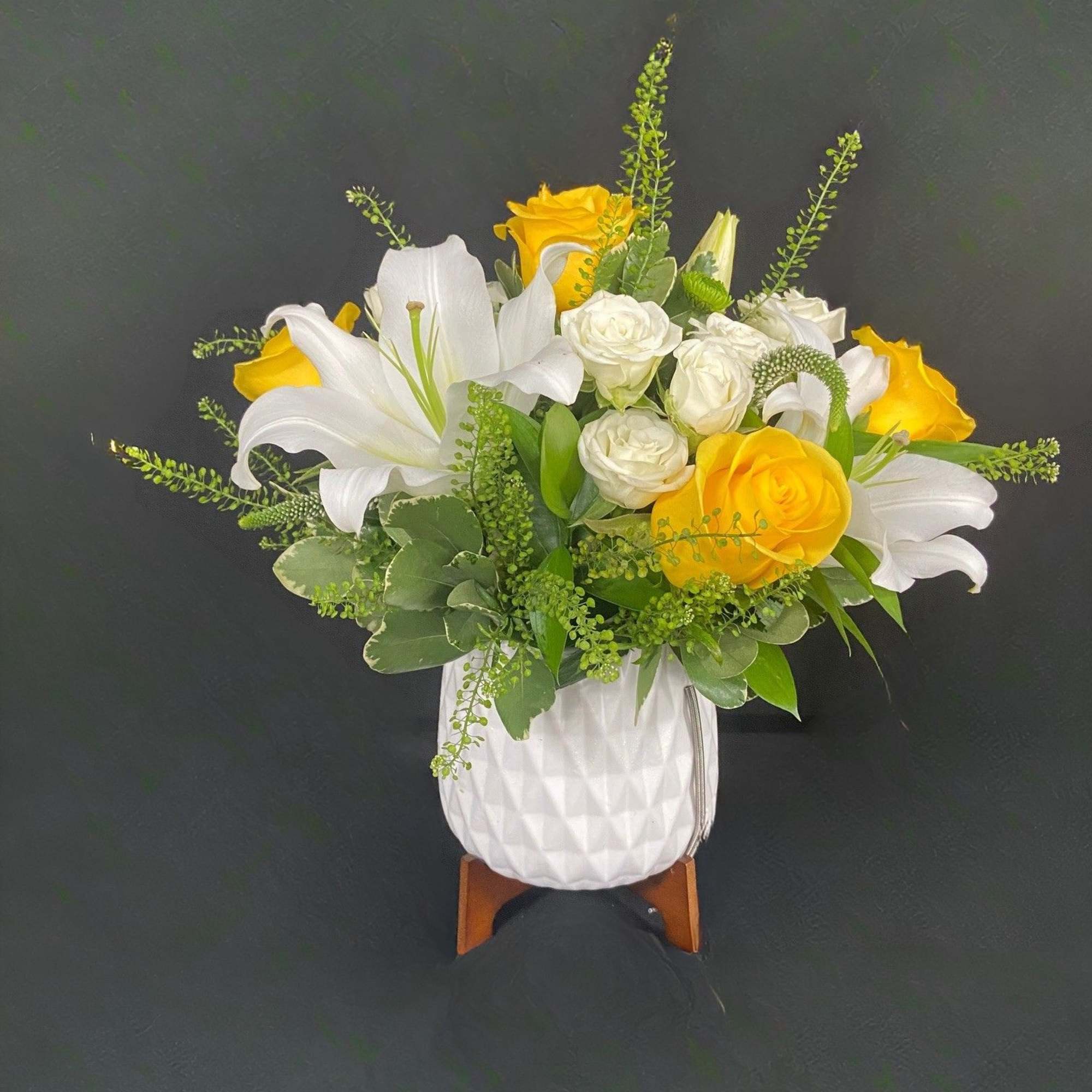 White lilies and yellow roses in a white vase