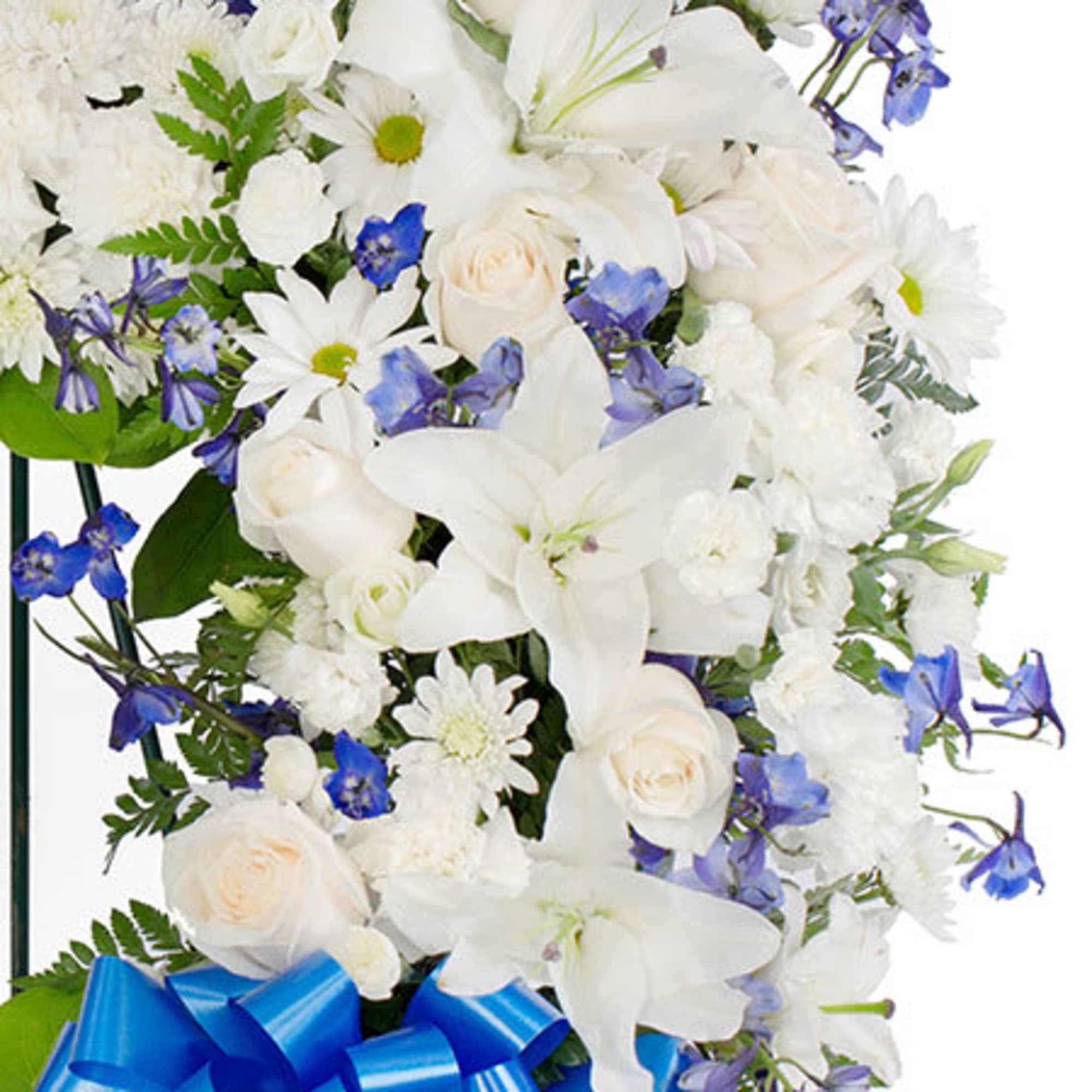 Spray of white lilies, roses, and daisies with blue accent flowers and a large blue bow
