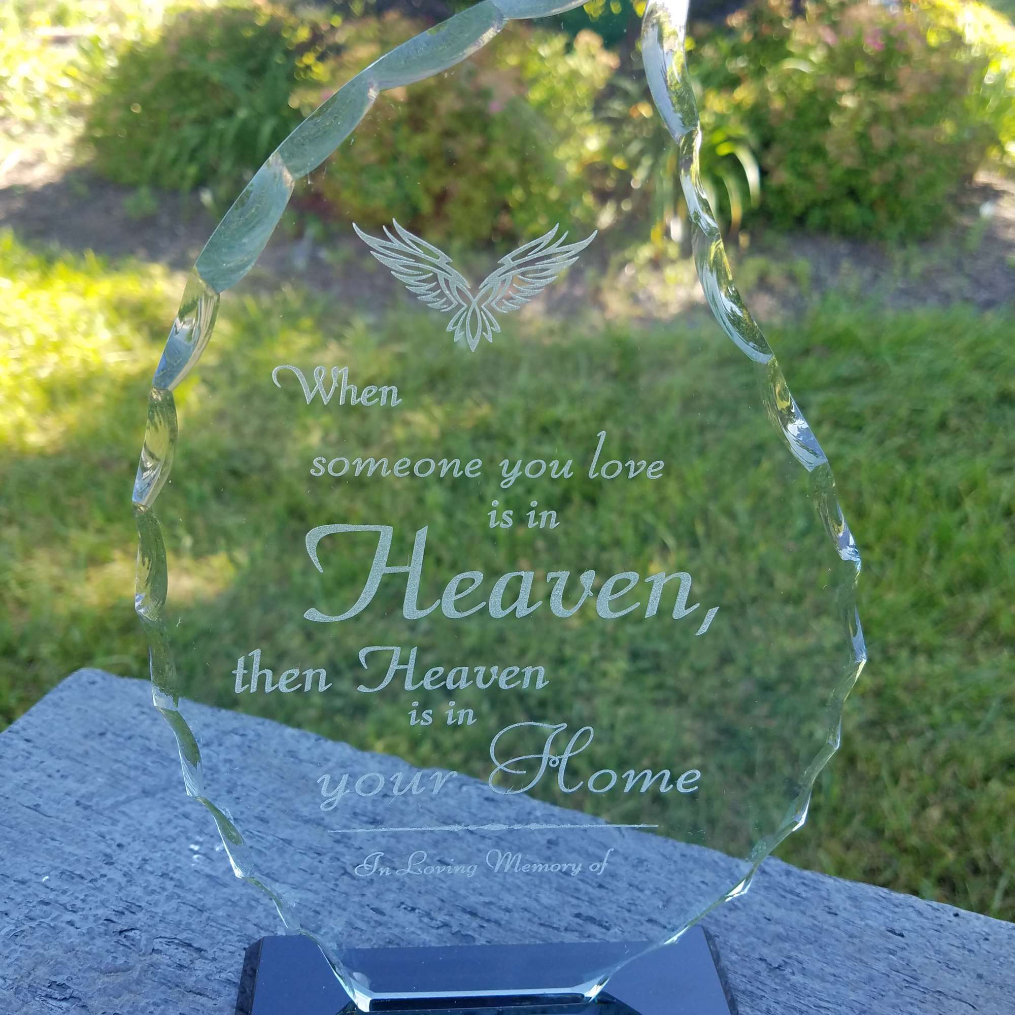 Engraved glass memorial plaque on a black base outdoors