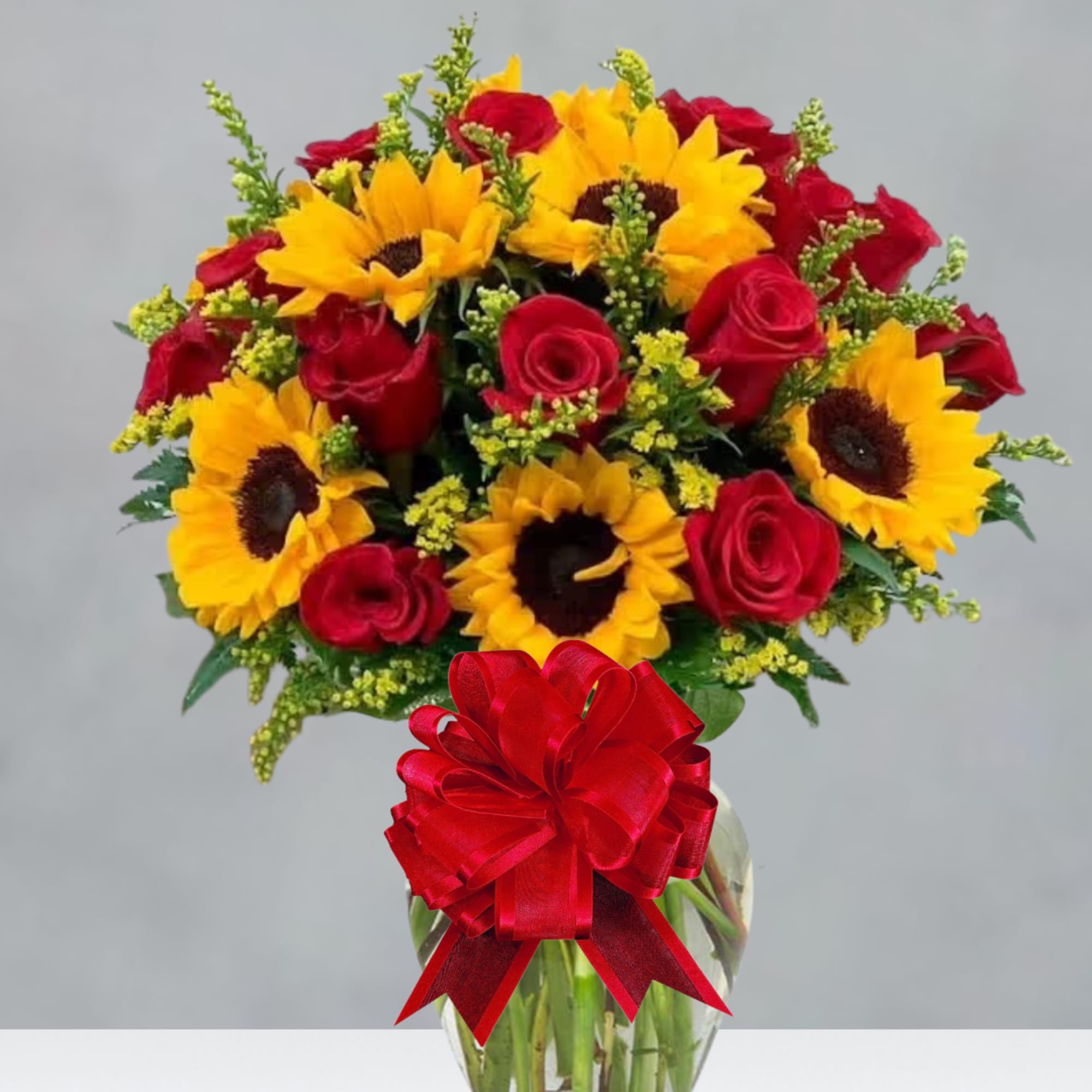 Bouquet of red roses and yellow sunflowers in a glass vase with a red bow