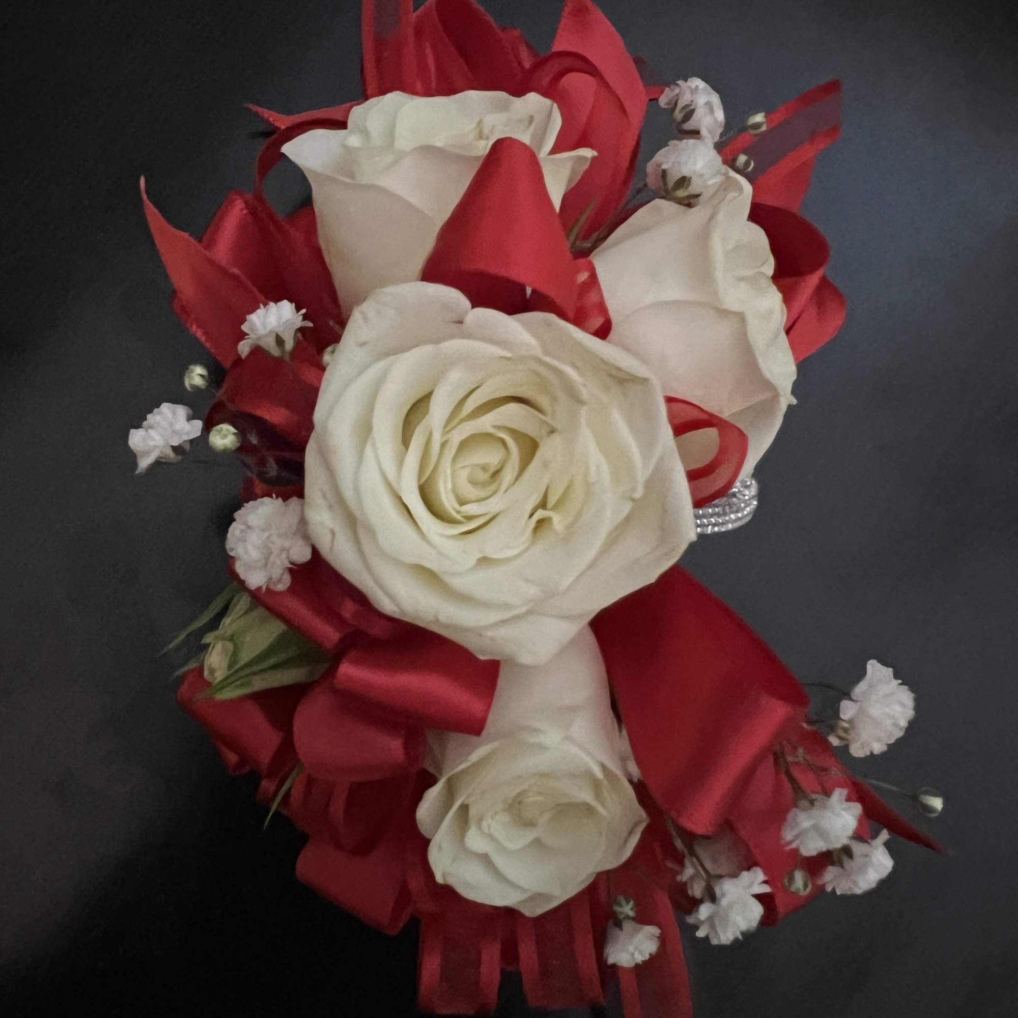 Red and white rose bouquet with ribbon accents on a dark background